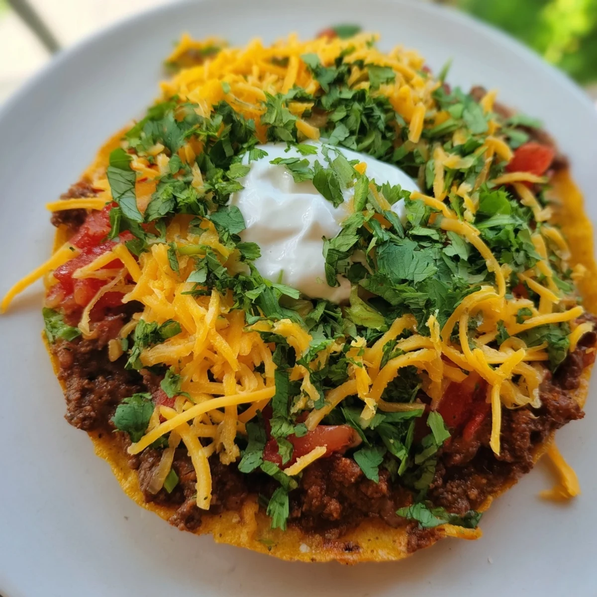 Sizzling beef tostadas topped with diced tomatoes, melted cheddar cheese, avocado slices, and a sprinkle of cilantro, ready for a family-style meal.