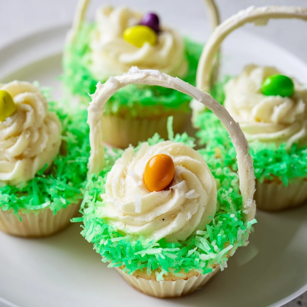 Freshly baked Easter Basket Cupcakes with Coconut Grass are arranged in a pastel display, with licorice basket handles tucked into the sweet, creamy frosting.