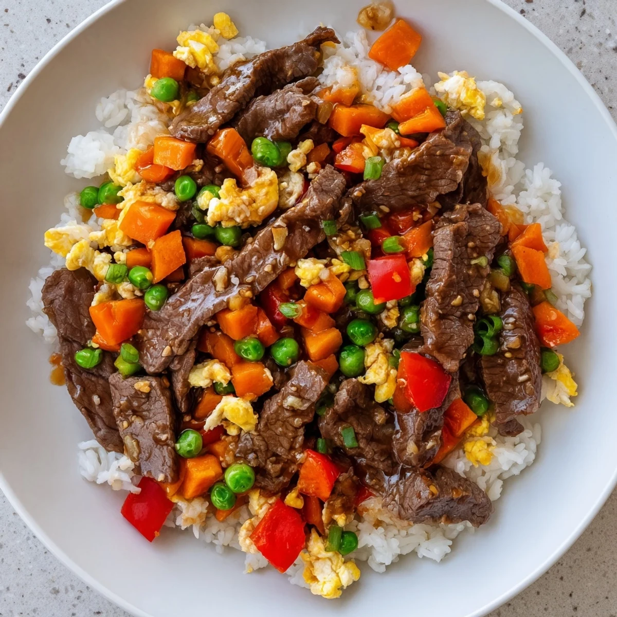 Beef Fried Rice with Vegetables plated with jasmine rice, scrambled eggs, and soy sauce drizzle.