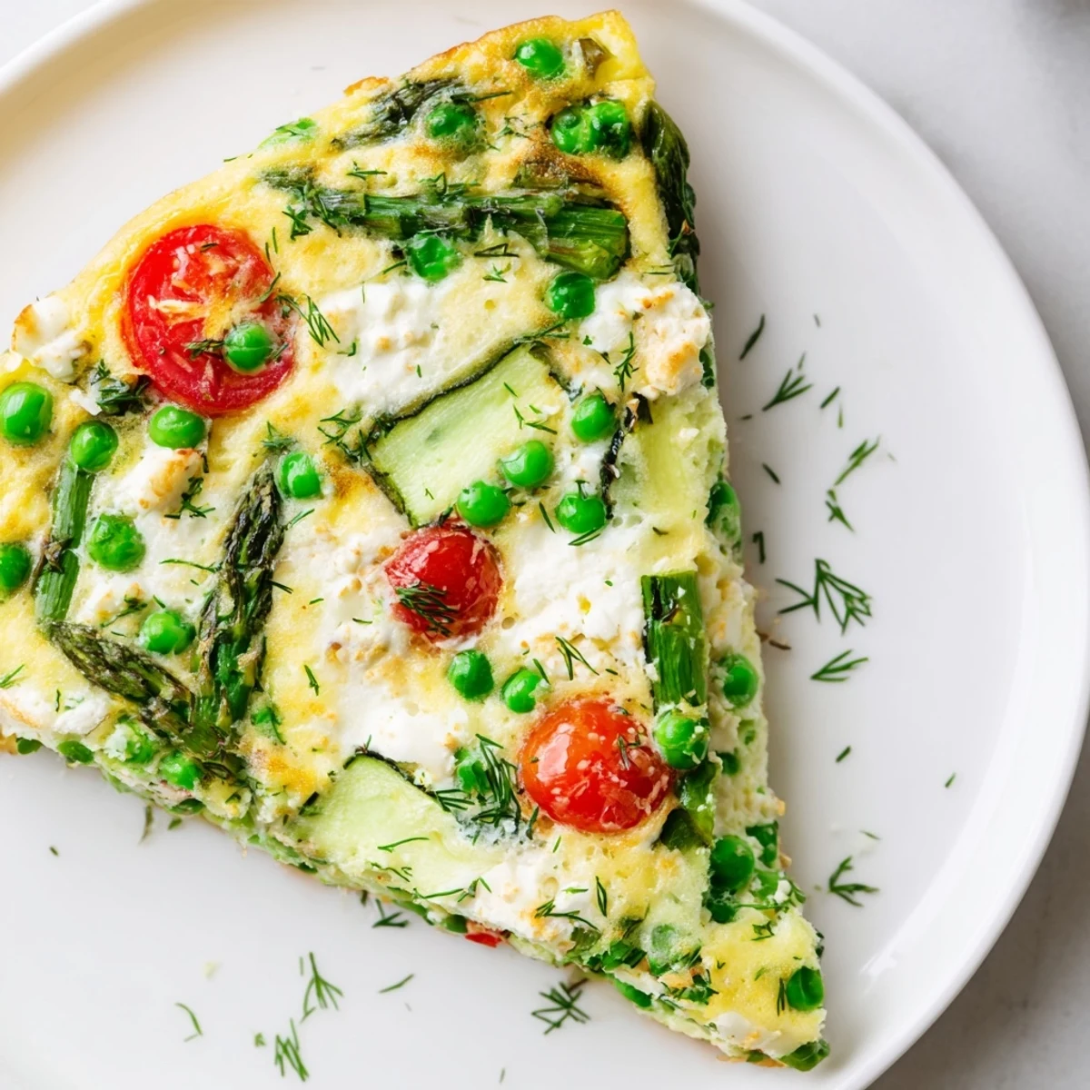 A close-up of Spring Vegetable Frittata with Herbs reveals colorful zucchini, peas, and cherry tomatoes nestled in a golden egg base.