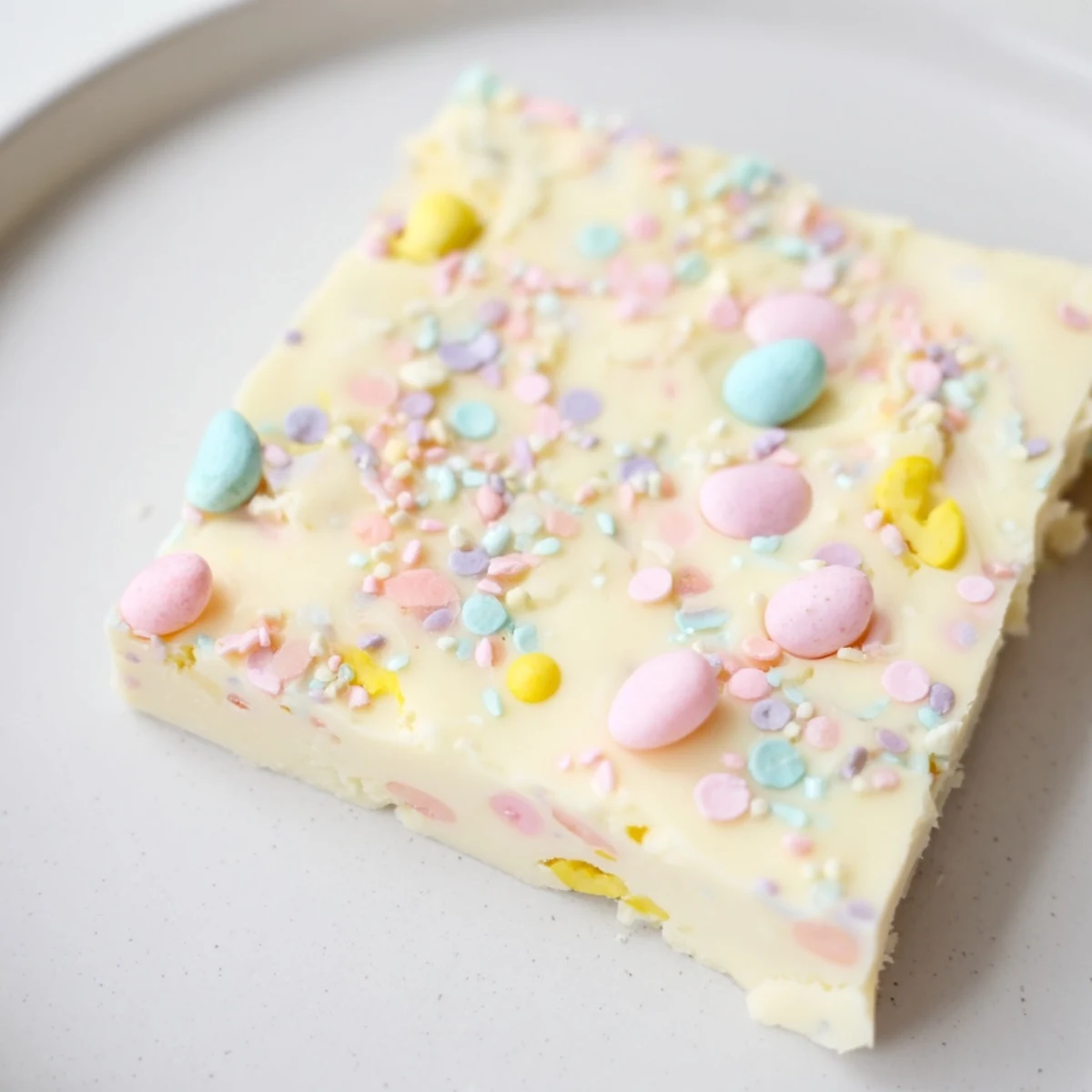 Easter Fudge squares with chopped pastel candies and sprinkles arranged on parchment paper.