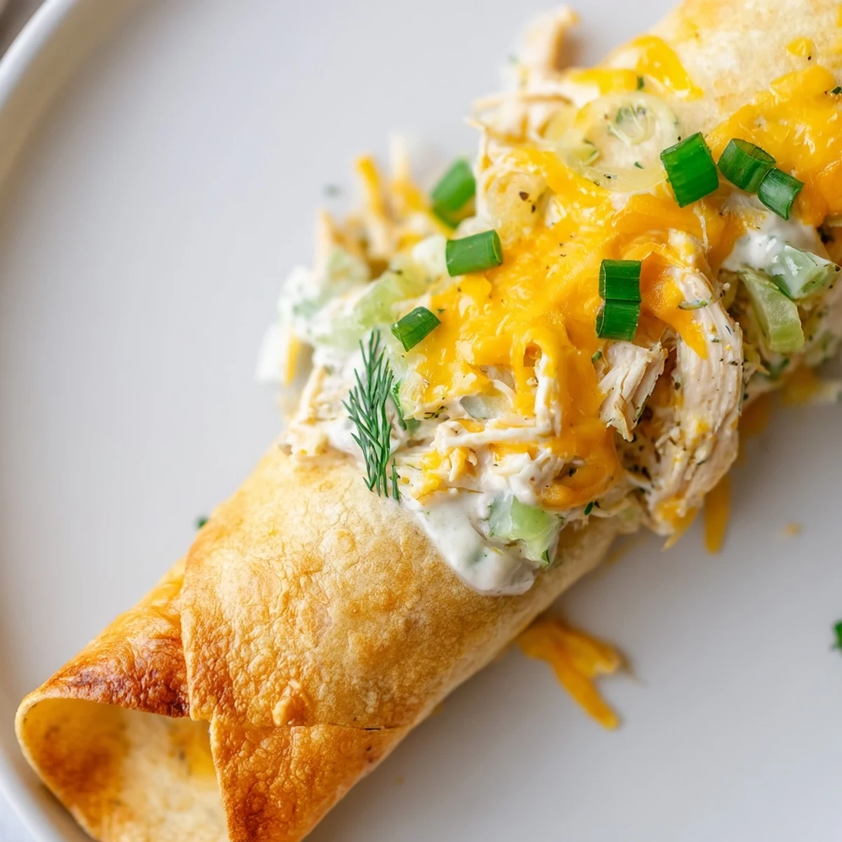 Golden-baked Dill Pickle Ranch Chicken Taquitos show their crispy tortilla shells on a white platter.