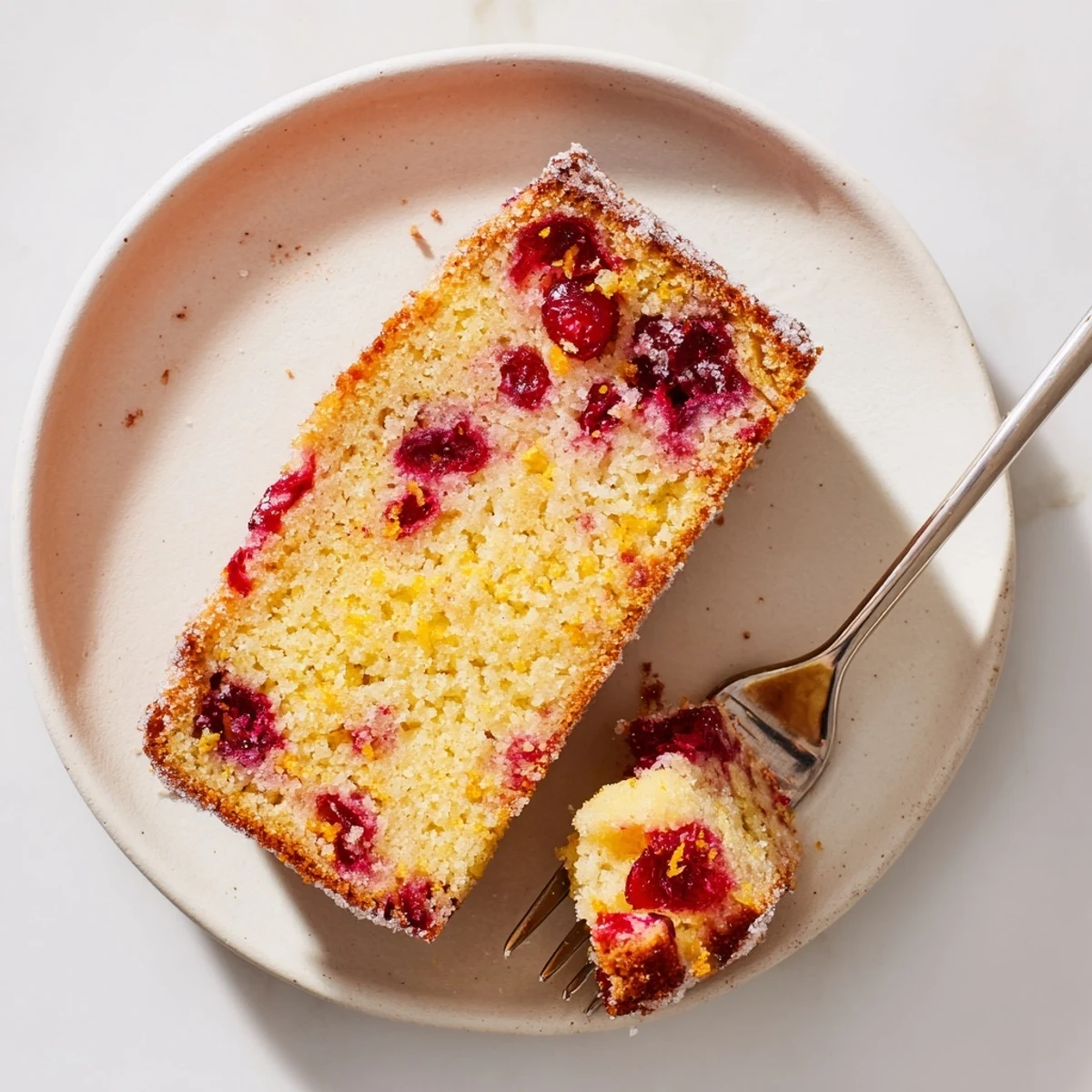 A freshly baked Cranberry Cake with orange zest crumbles, showing a moist crumb and tart red berries.