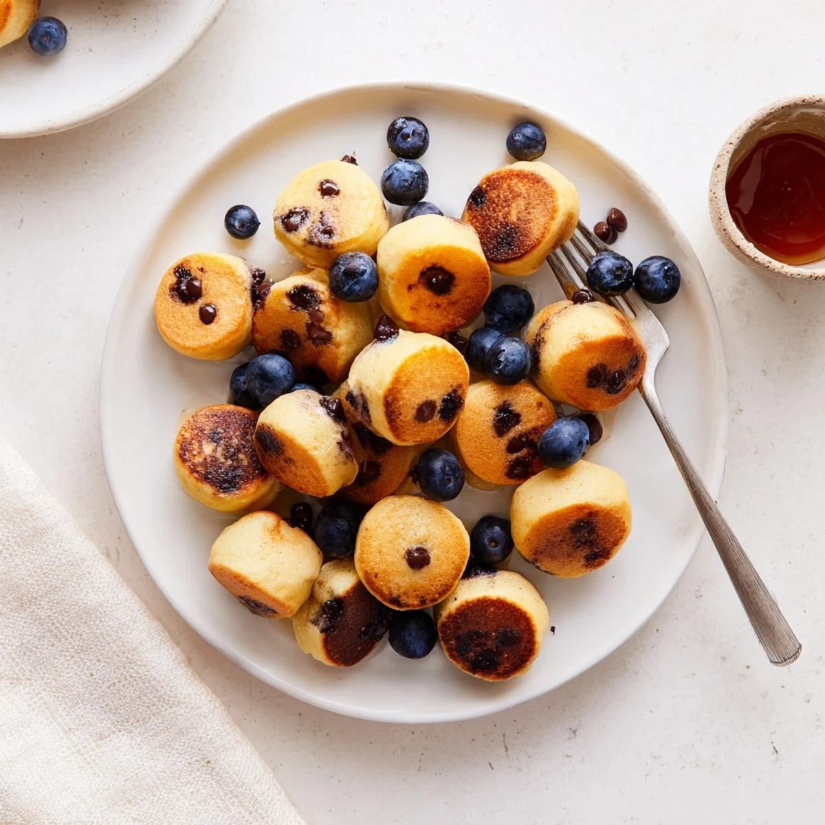 Fluffy golden Pancake Poppers stacked high, dusted with powdered sugar and drizzled with warm maple syrup for a cozy breakfast treat.