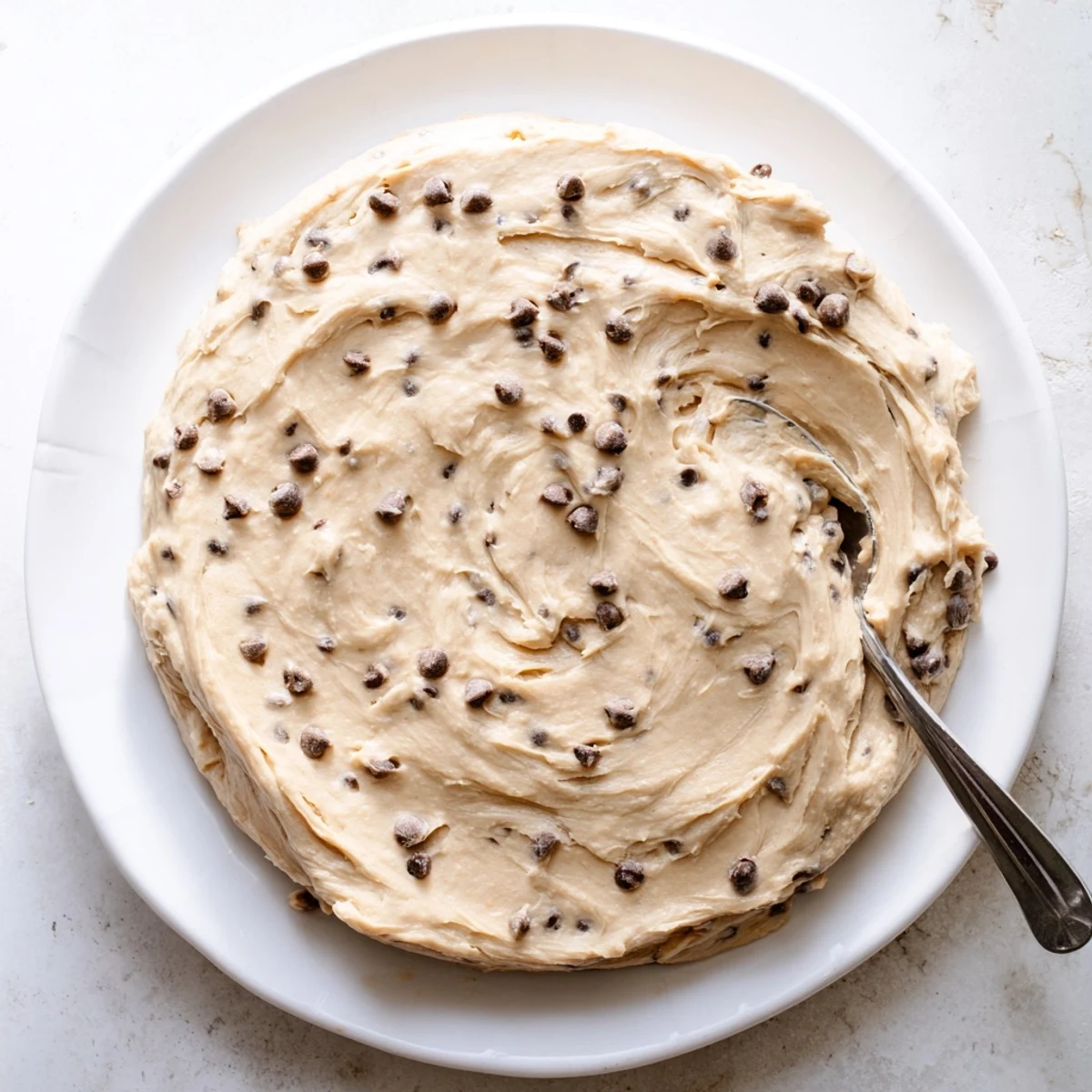 A close-up view of Cookie Dough Frosting swirled on a spatula, showing brown sugar specks and smooth buttery texture.