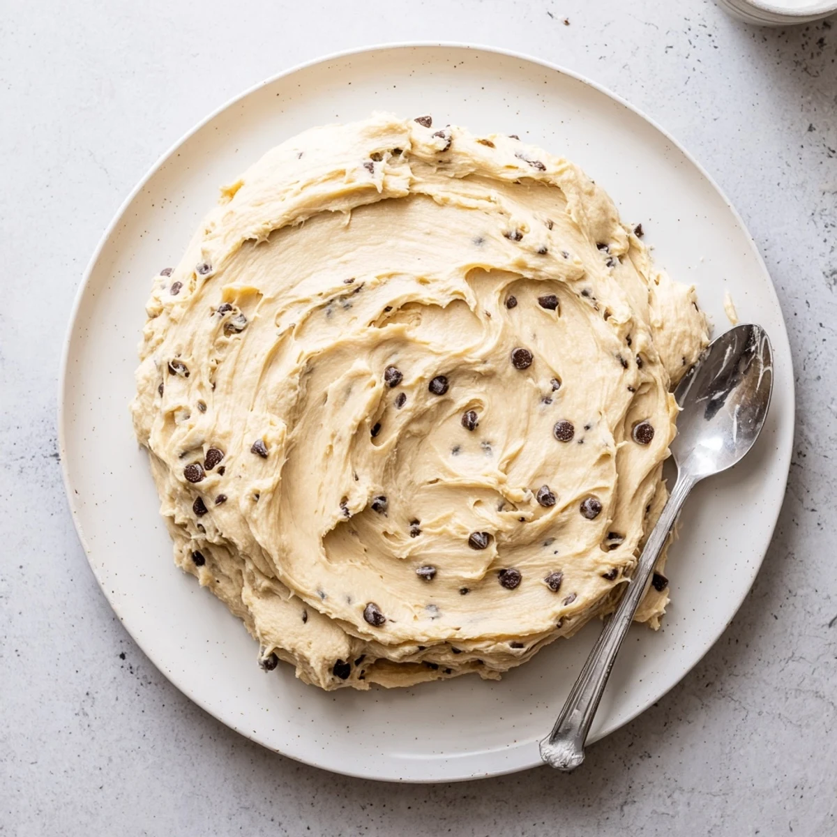 A generous dollop of Cookie Dough Frosting melting slightly over a warm brownie, with chocolate chips glistening on top.