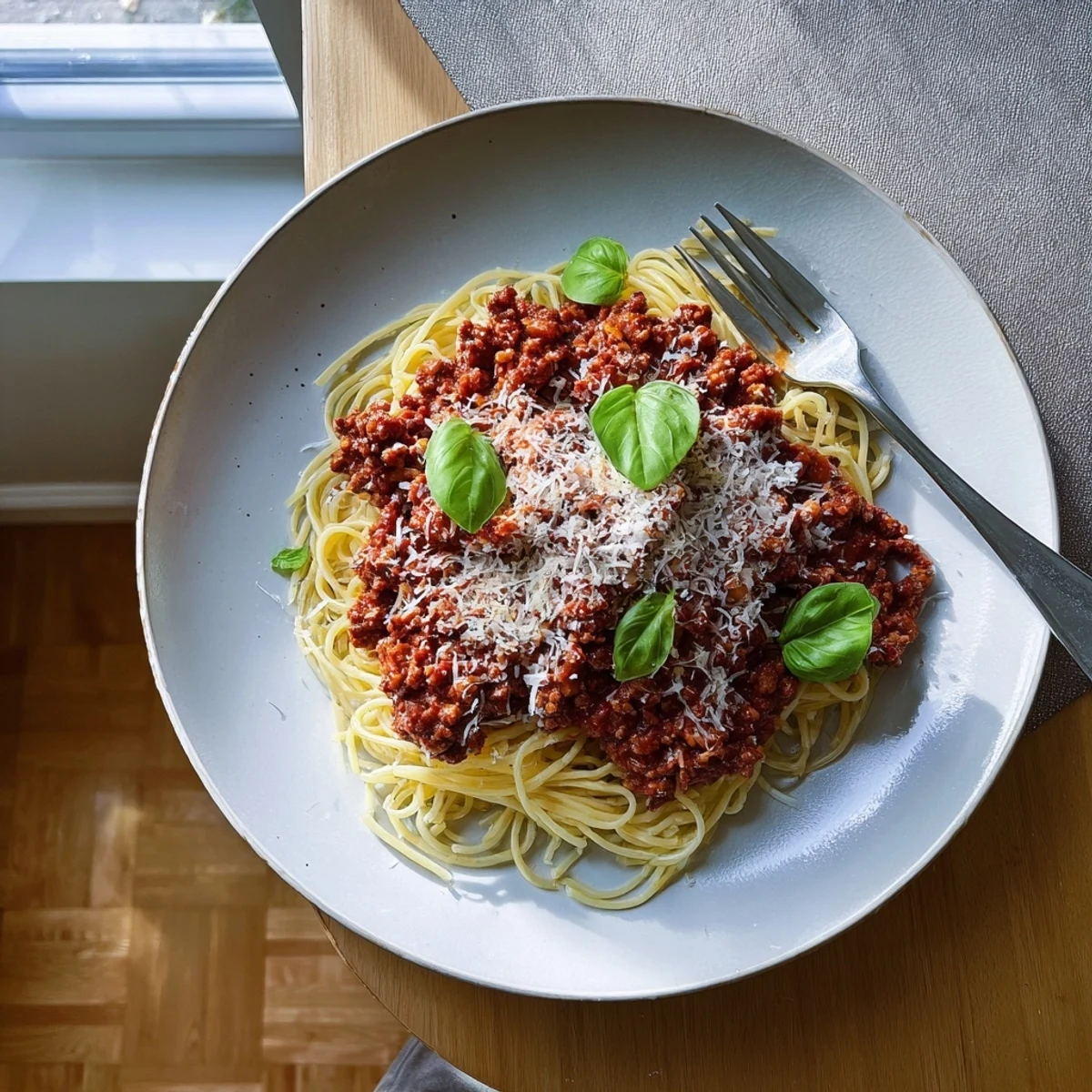 Steaming plate of The Bear Spaghetti topped with fresh basil and melted Parmesan cheese.