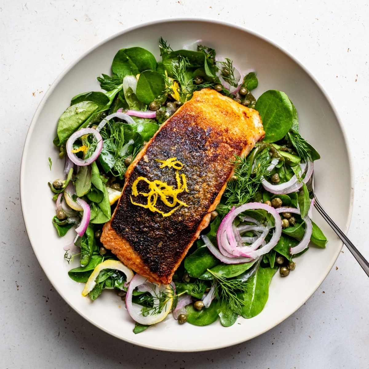 Close-up of perfectly seared Tasmanian Atlantic salmon with crackling skin beside fresh greens and bright lemon zest.