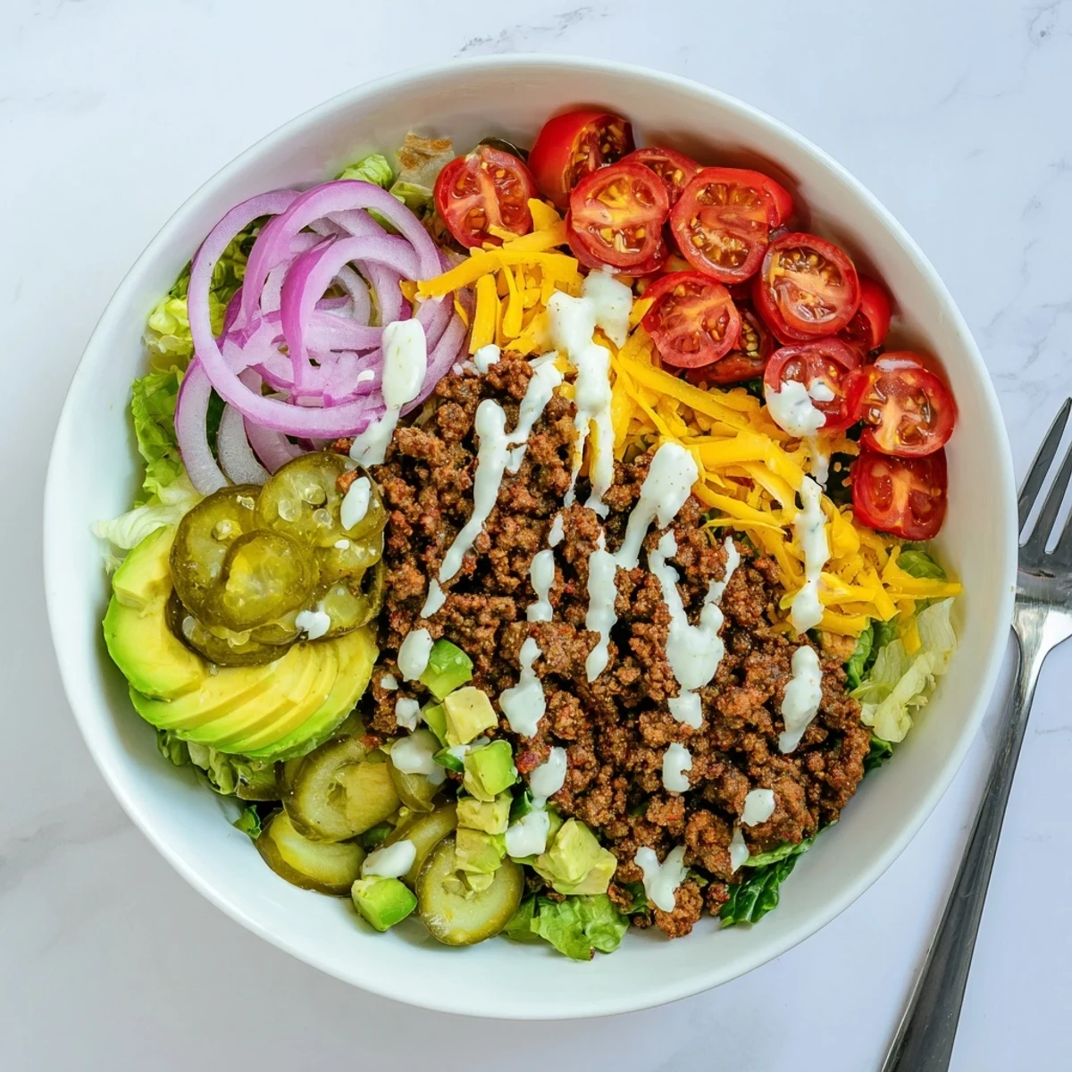 Serving Burger Bowls with golden ground beef, shredded cheese, pickles, and tomatoes beside creamy homemade dressing.