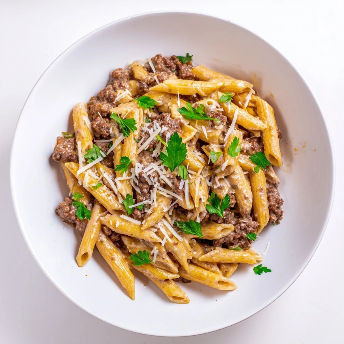 Golden creamy beef pasta topped with fresh parsley and grated Parmesan cheese