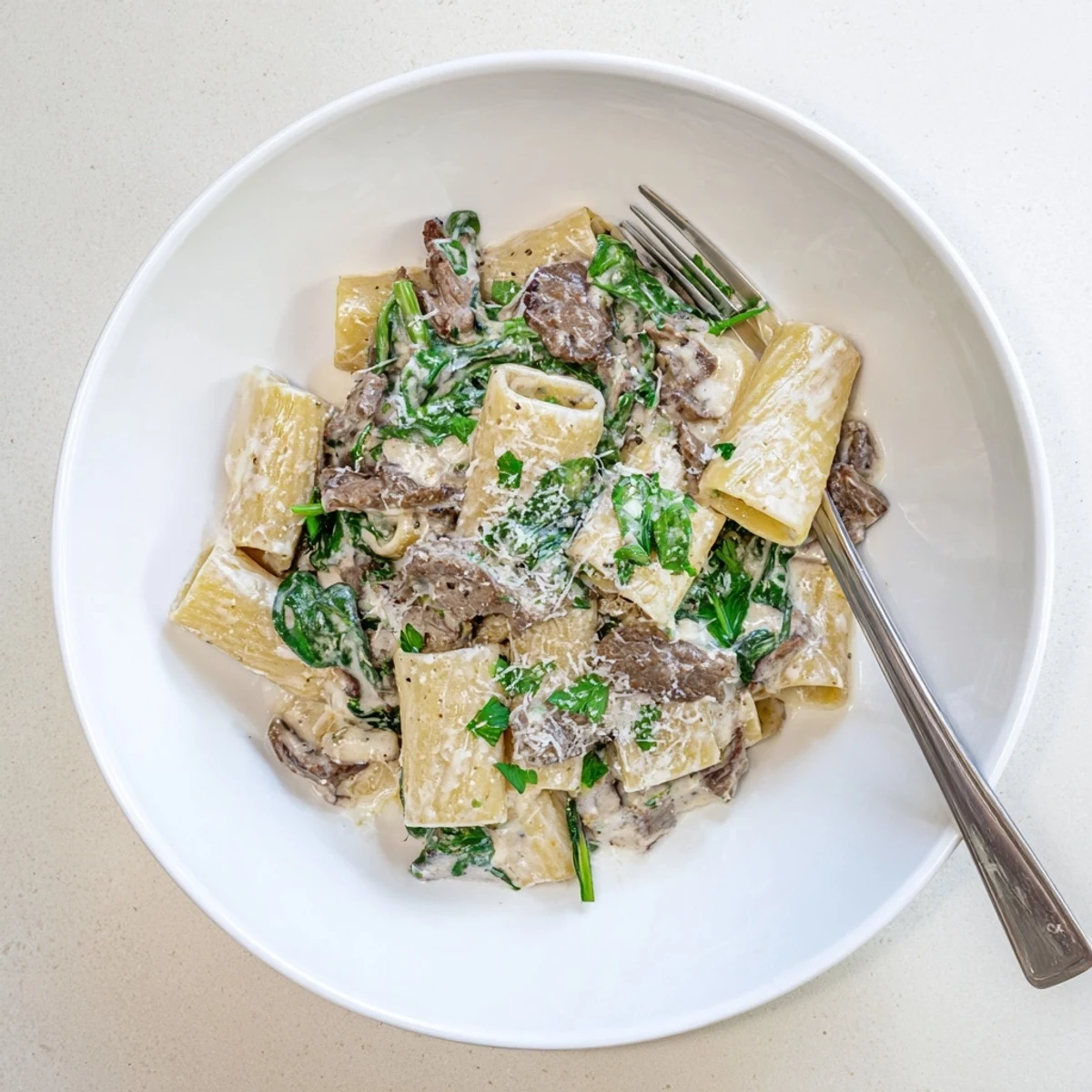 Garnished creamy high protein beef pasta with al dente noodles browned beef and fresh parsley sprinkled on top