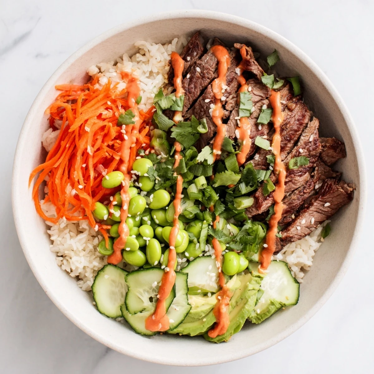 Sliced marinated flank steak bowl with fresh vegetables avocado and spicy sauce over rice