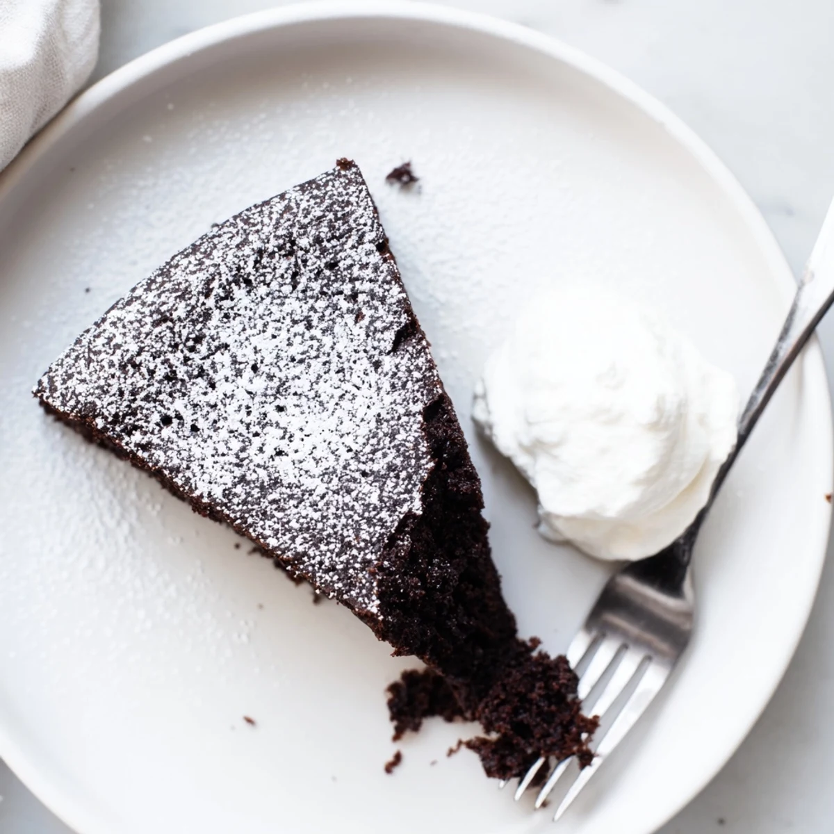 Moist Guinness chocolate cake with powdered sugar dusting on a white serving plate