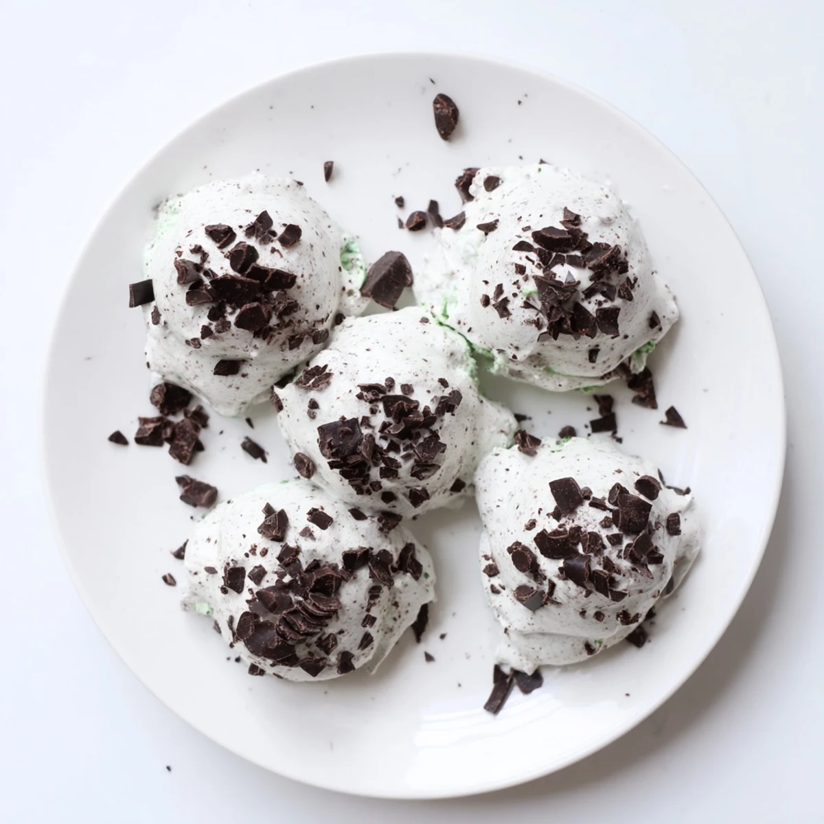Dreamy dark chocolate and mint chip clouds meringue cookies piled on a white serving plate