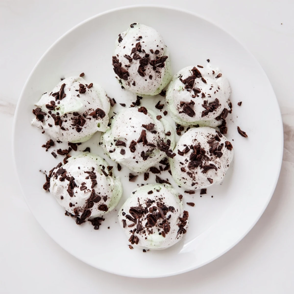 Glossy dark chocolate and mint chip meringue clouds ready for baking on two sheets