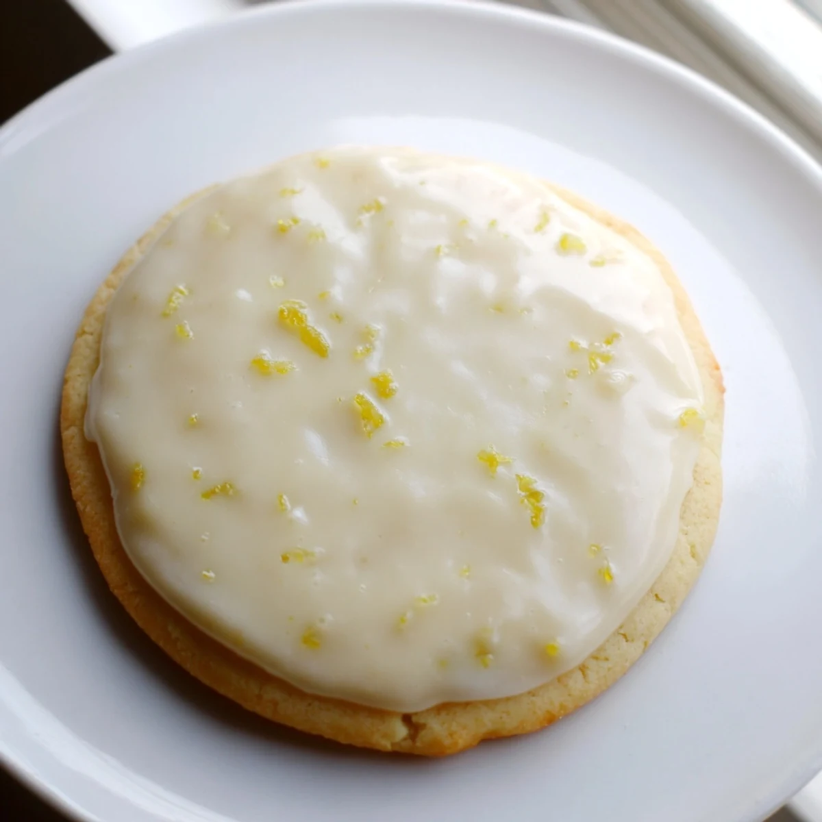 Buttery lemon frosted cookies arranged on serving tray with smooth lemon glaze coating