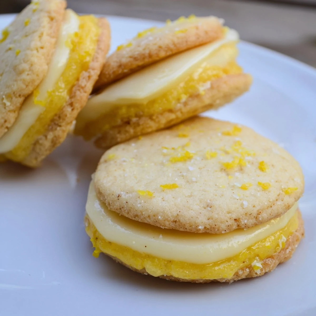 Plant-based lemon sandwich cookies revealing bright yellow curd layer between crisp rounds