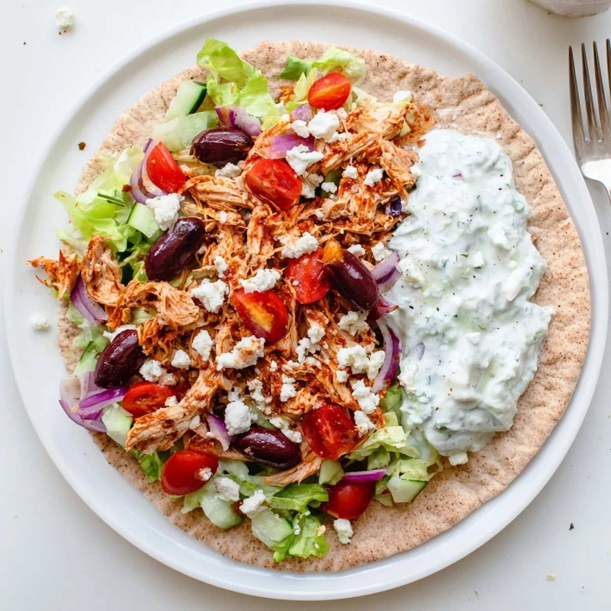 Flavorful Crockpot Greek Chicken Pitas topped with fresh lettuce, tomatoes, and creamy homemade tzatziki