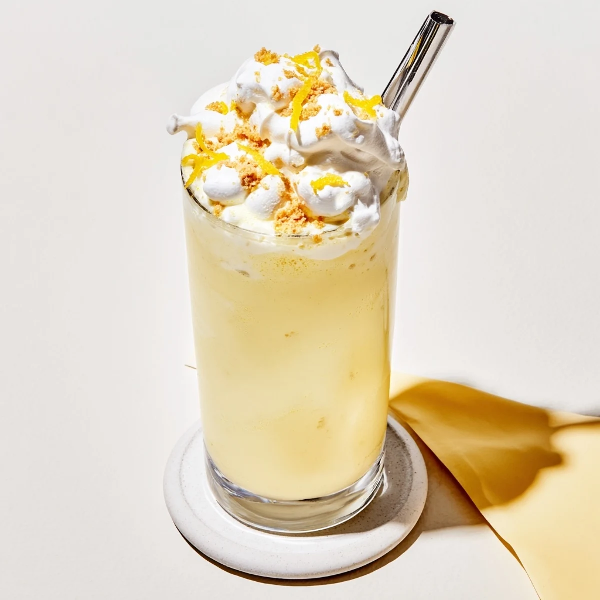 Tall chilled glass showcasing layered lemon meringue frappé with cloudlike meringue topping