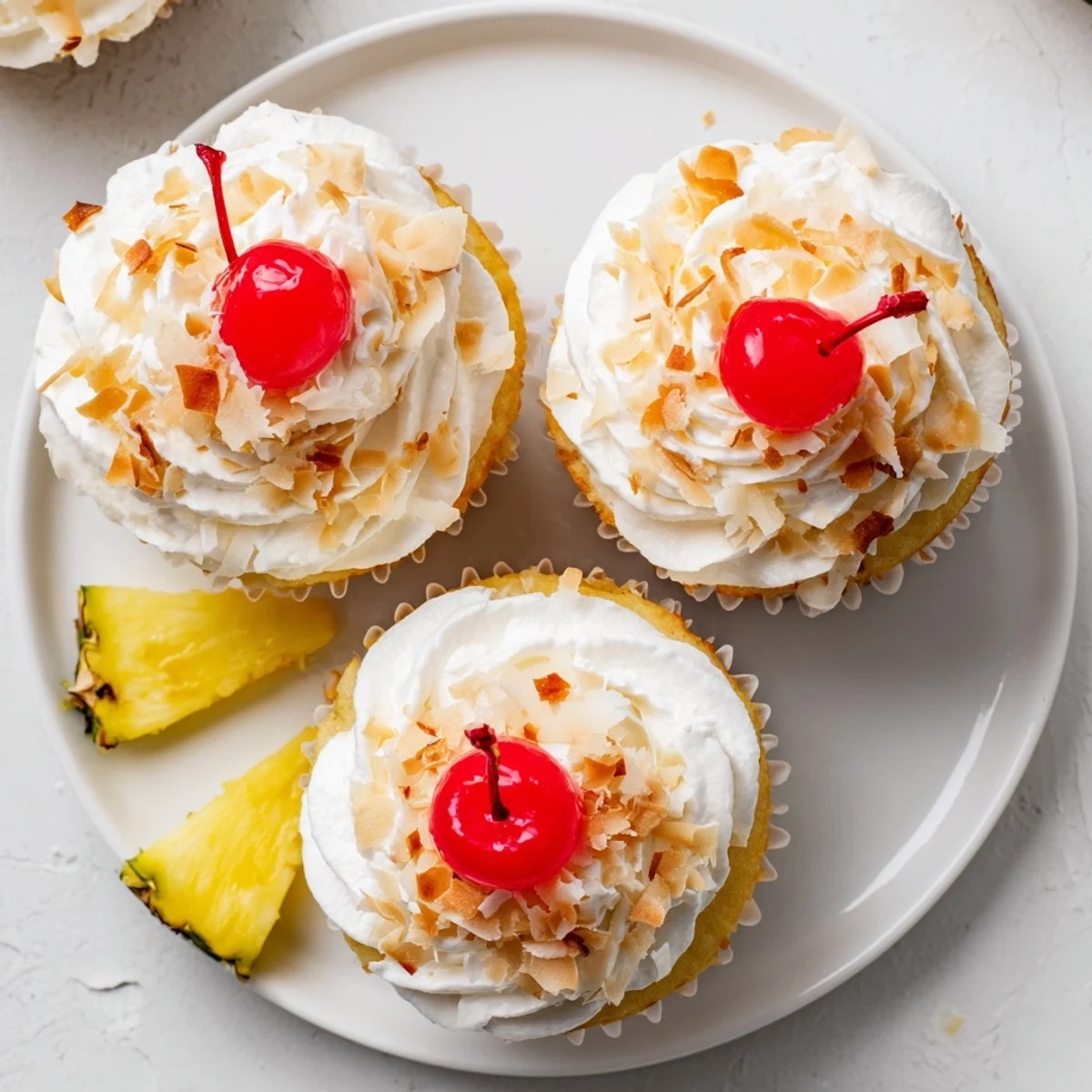 Moist pineapple and coconut Pina Colada cupcakes piped with creamy white frosting and garnish