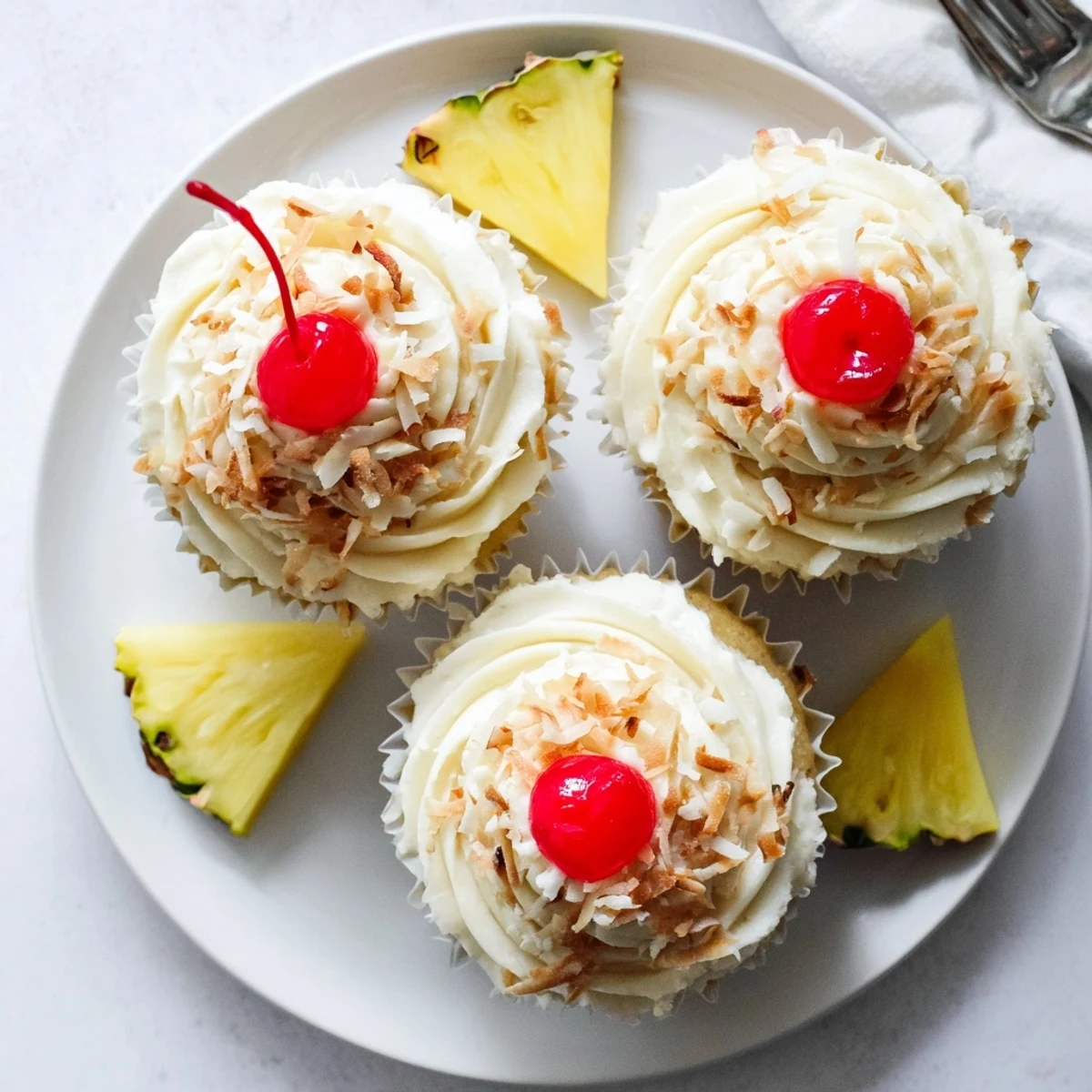 Tropical Pina Colada cupcakes crowned with whipped coconut buttercream and maraschino cherries