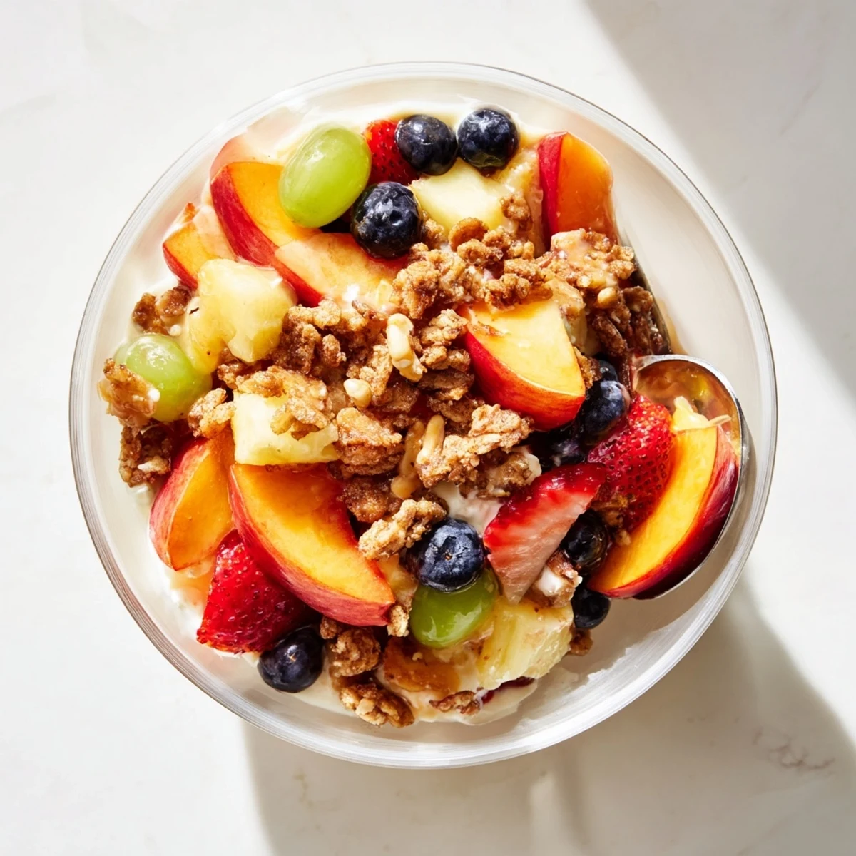 Golden peach cobbler cheesecake fruit salad bowl topped with cinnamon crumbles and fresh berries