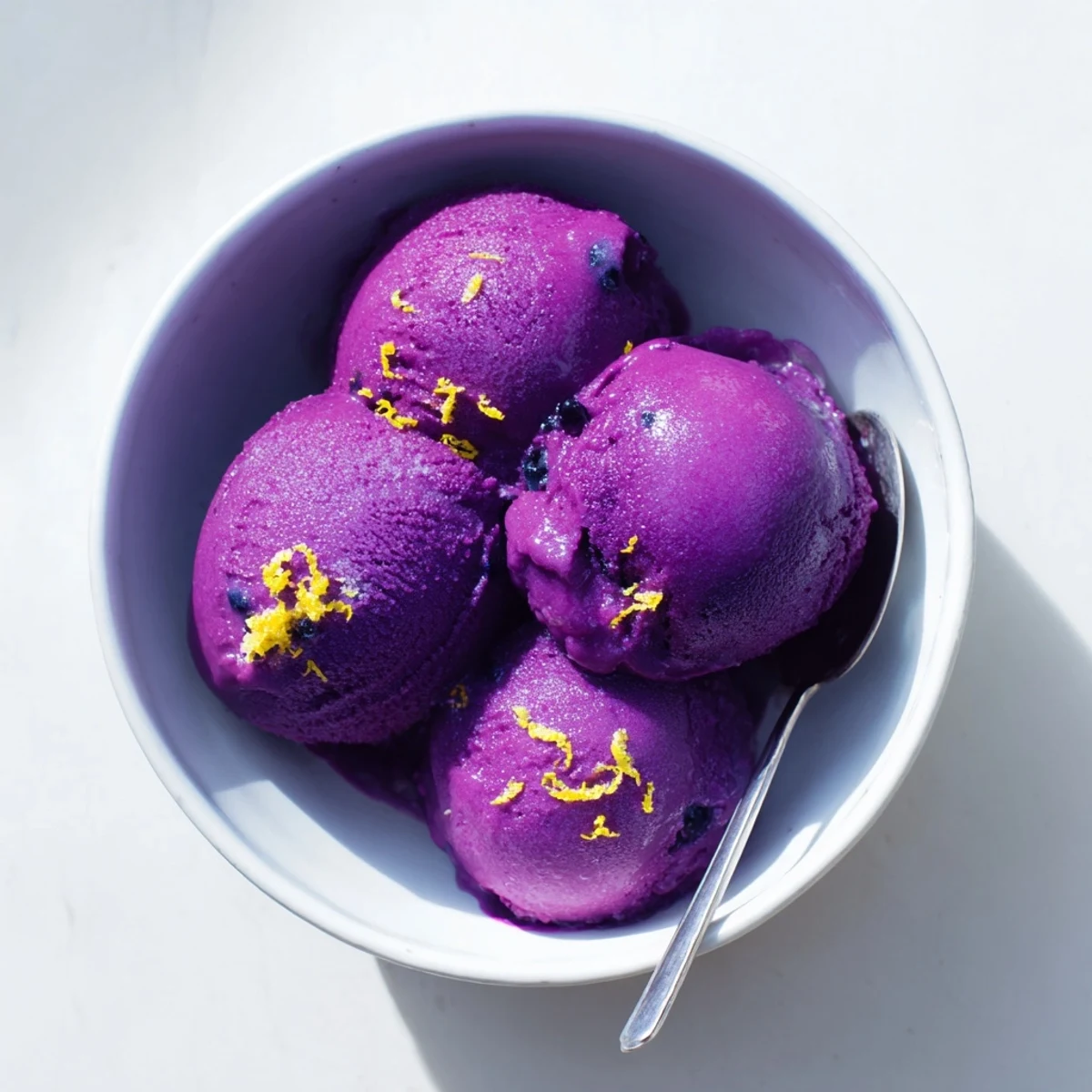 Purple no churn blueberry lemon sorbet scooped into a chilled bowl with fresh mint garnish