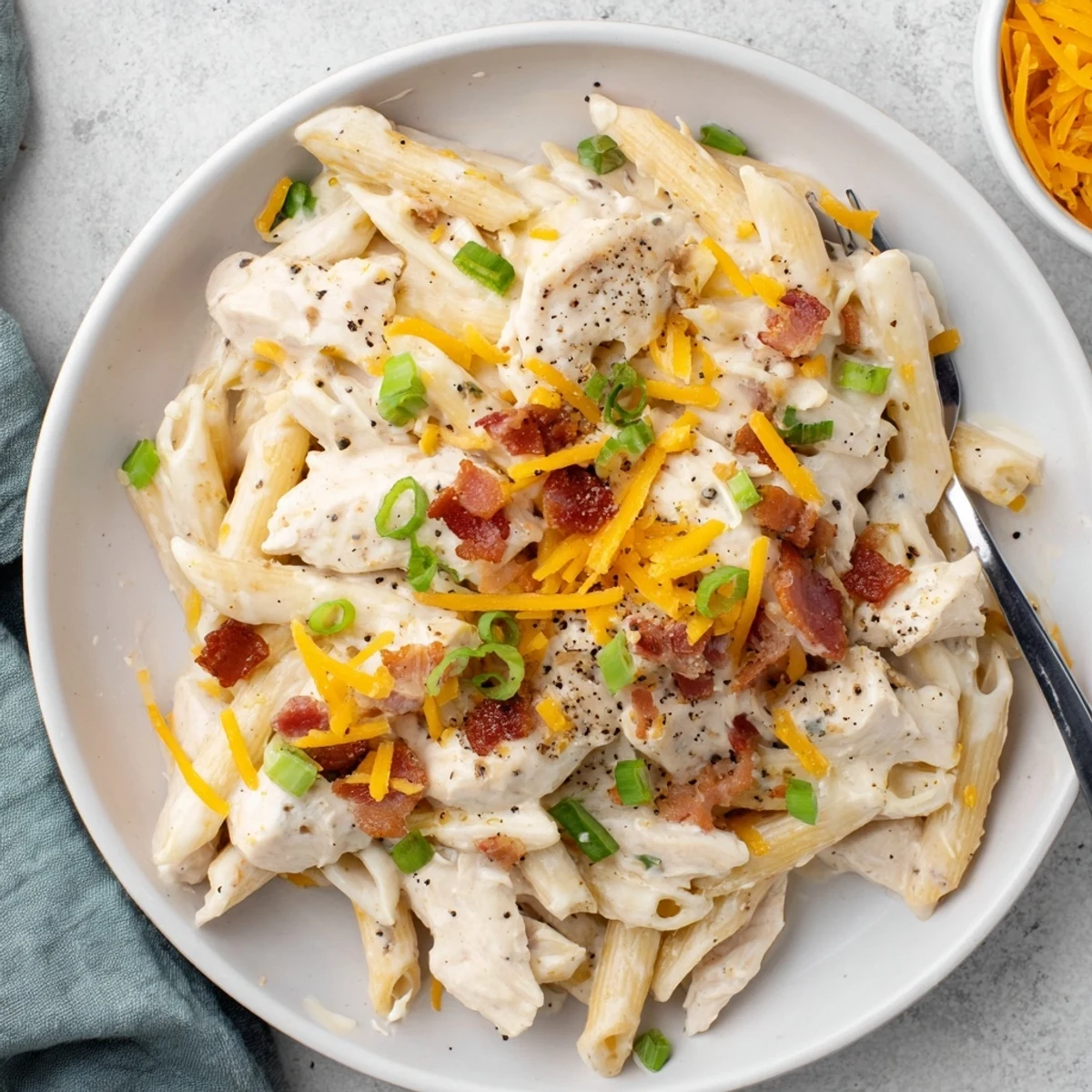 Bowl of comforting crack chicken pasta with tender shredded chicken, green onions, and ranch-seasoned cream sauce