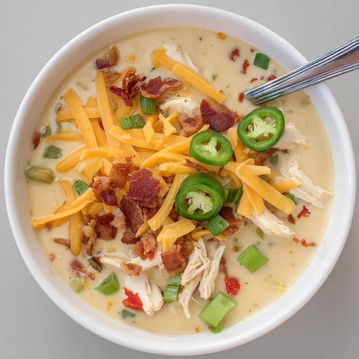 Steaming bowl of spicy jalapeno popper chicken soup featuring tender shredded chicken in a velvety cream cheese broth