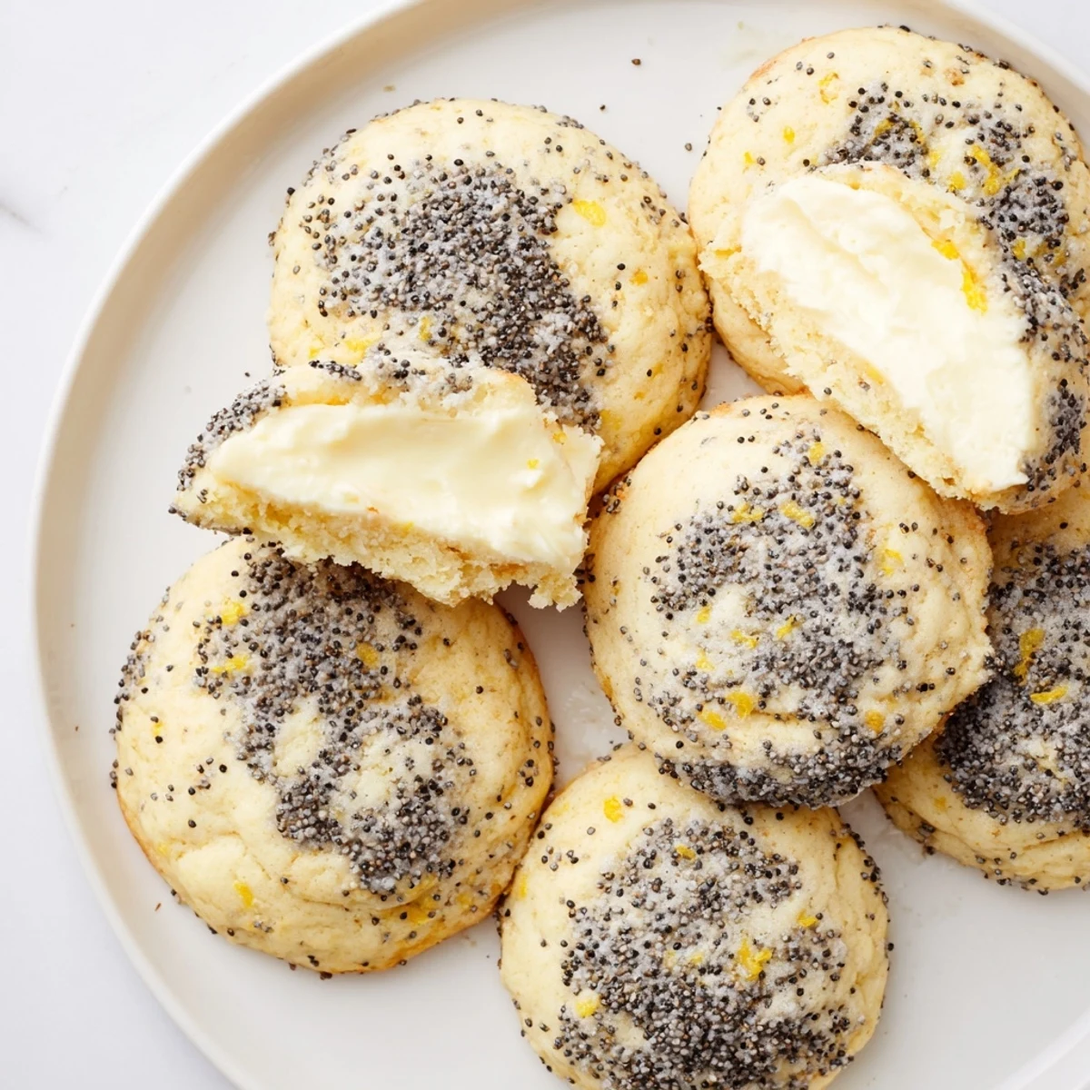 Golden lemon poppy seed cheesecake cookies with creamy centers on a white plate