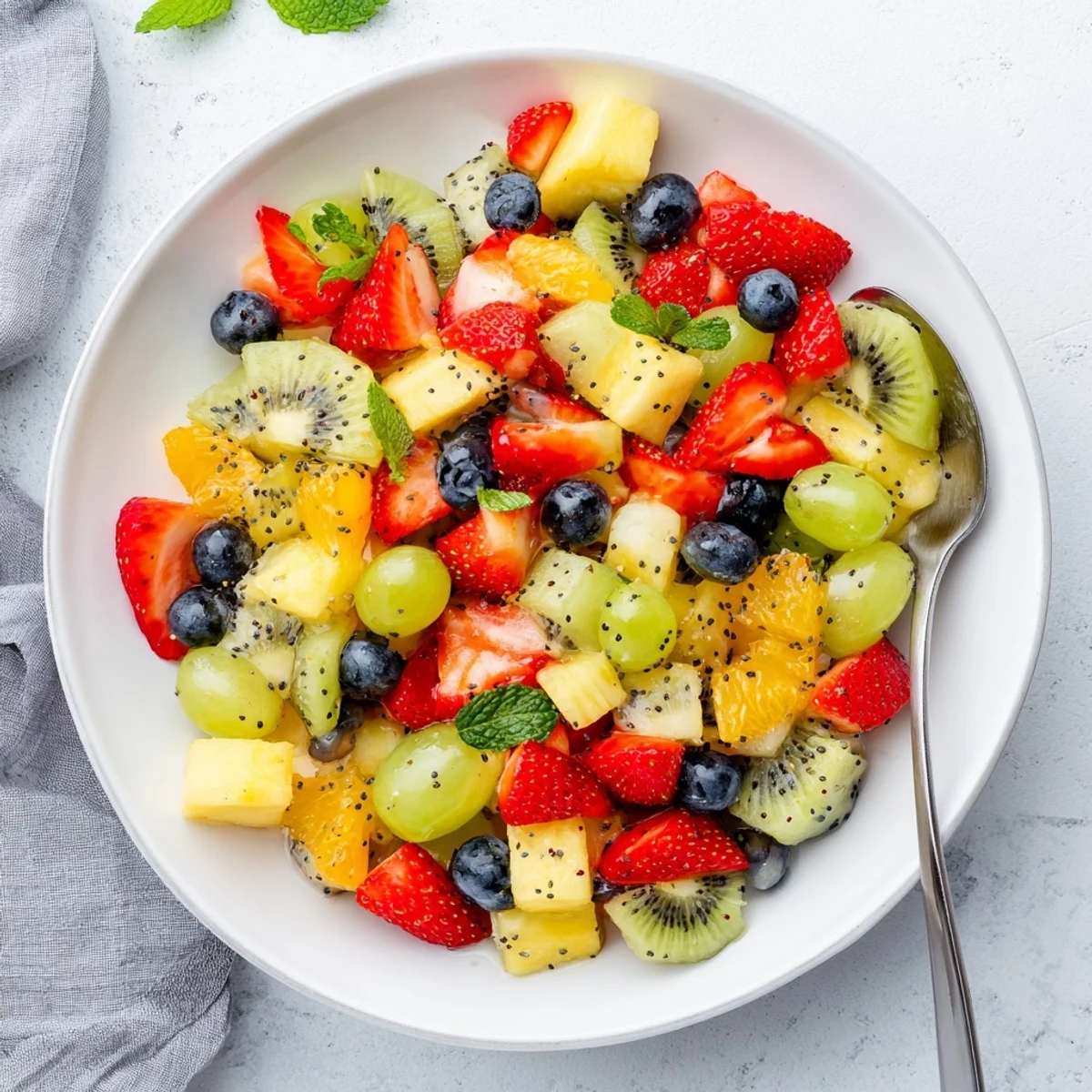Fresh Easter fruit salad displaying sliced kiwi, berries, pineapple chunks, and mandarin oranges in honey dressing