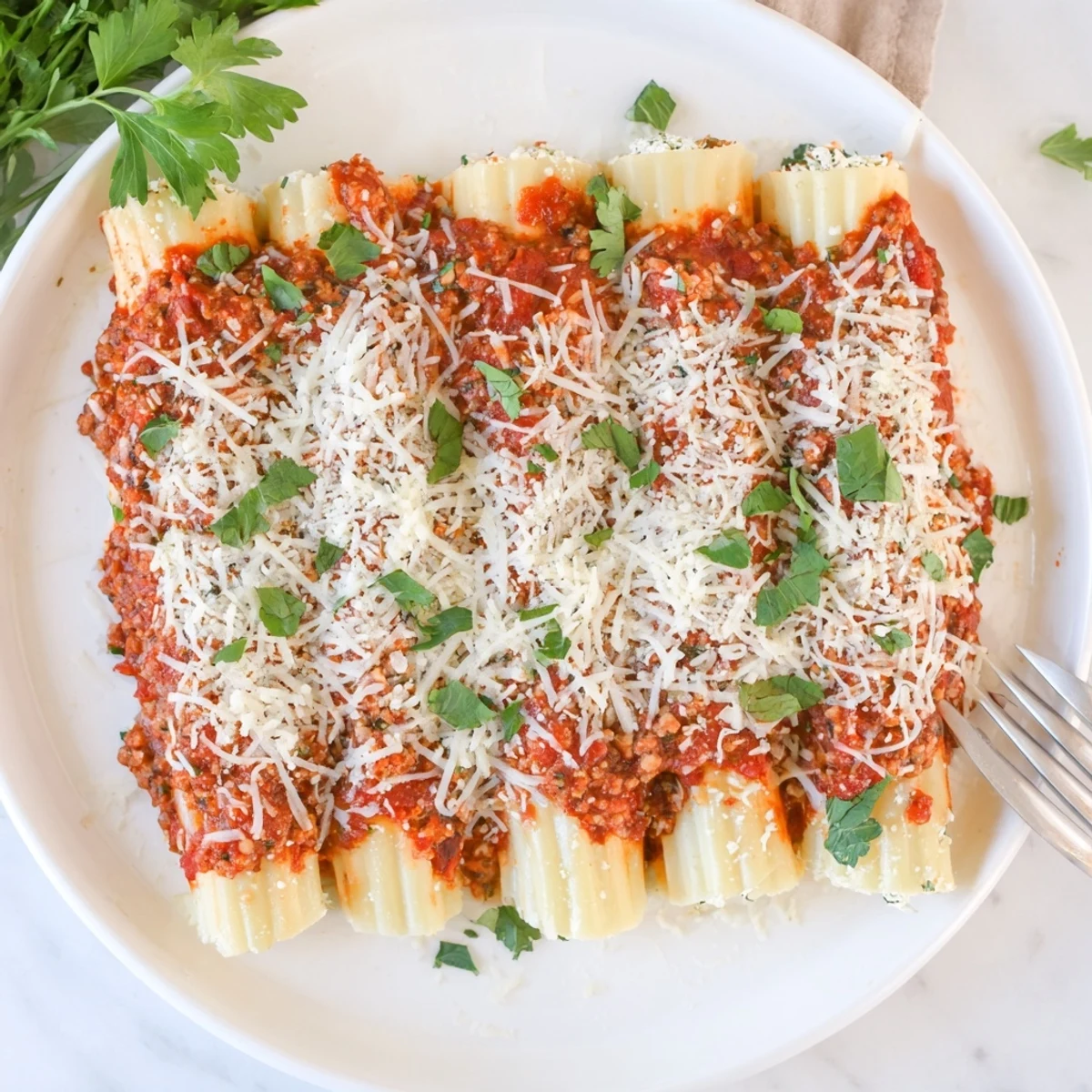 Italian comfort food dish featuring cheese stuffed manicotti swimming in flavorful seasoned meat sauce