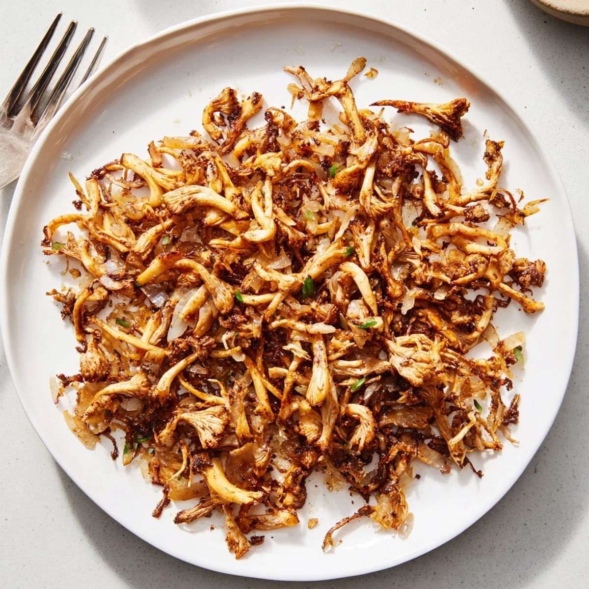 Golden shredded vegan carnitas with mushrooms piled high on warm corn tortillas