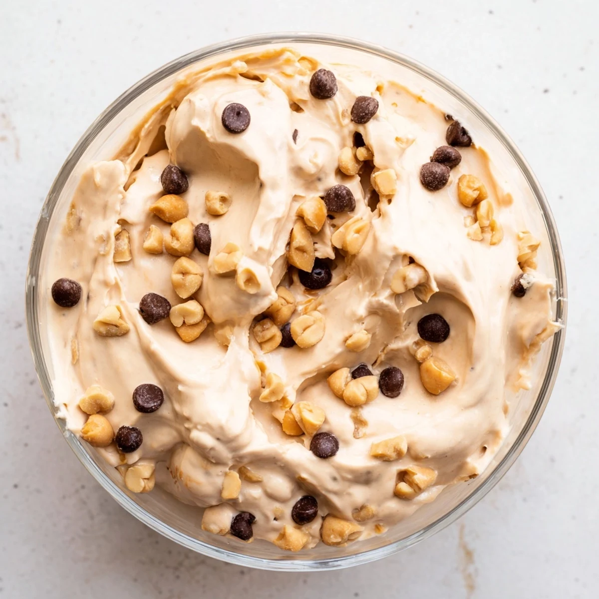 Creamy peanut butter mousse topped with mini chocolate chips and crunchy roasted peanuts in a clear glass