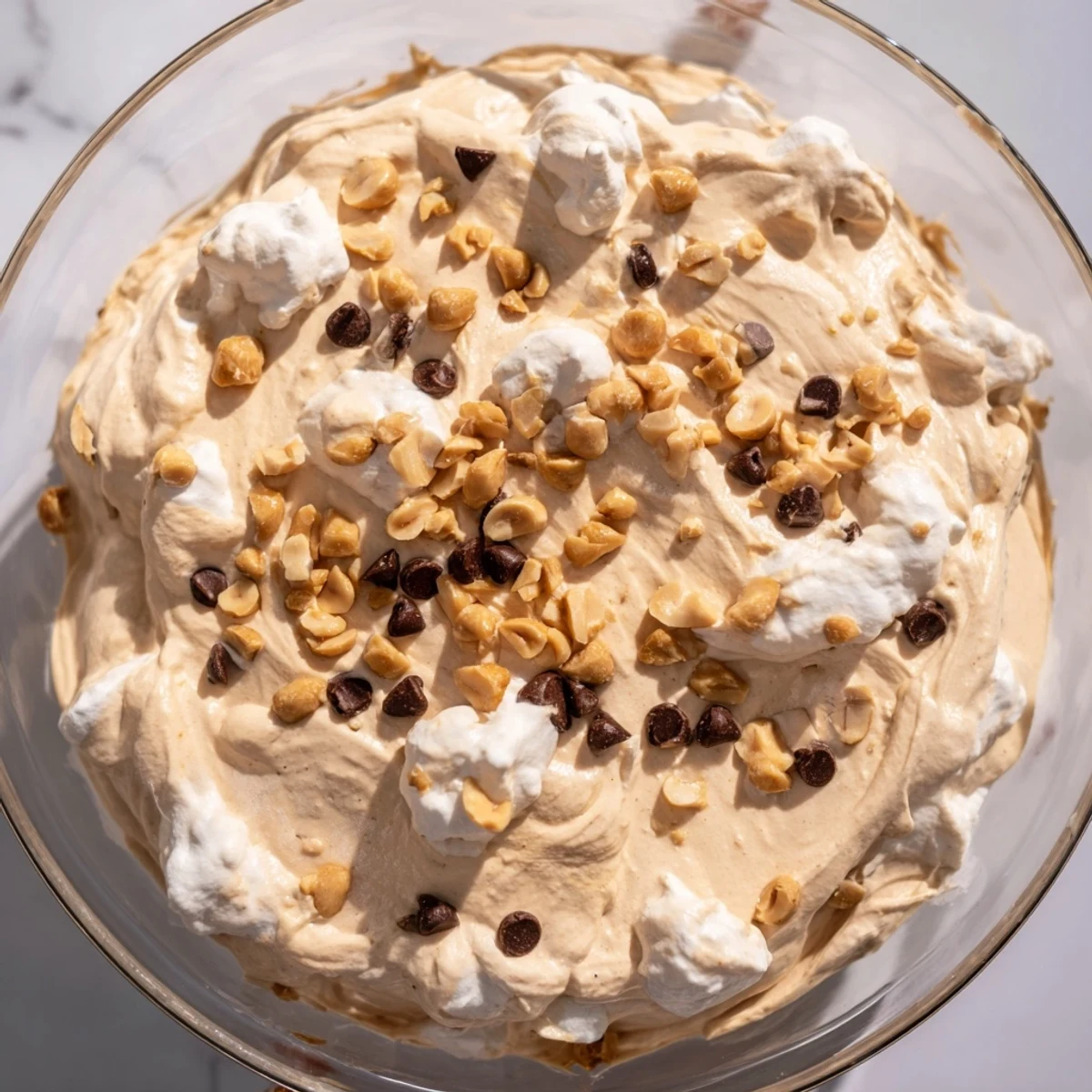 Velvety smooth peanut butter mousse with whipped cream swirling through a white ramekin garnished with peanut pieces