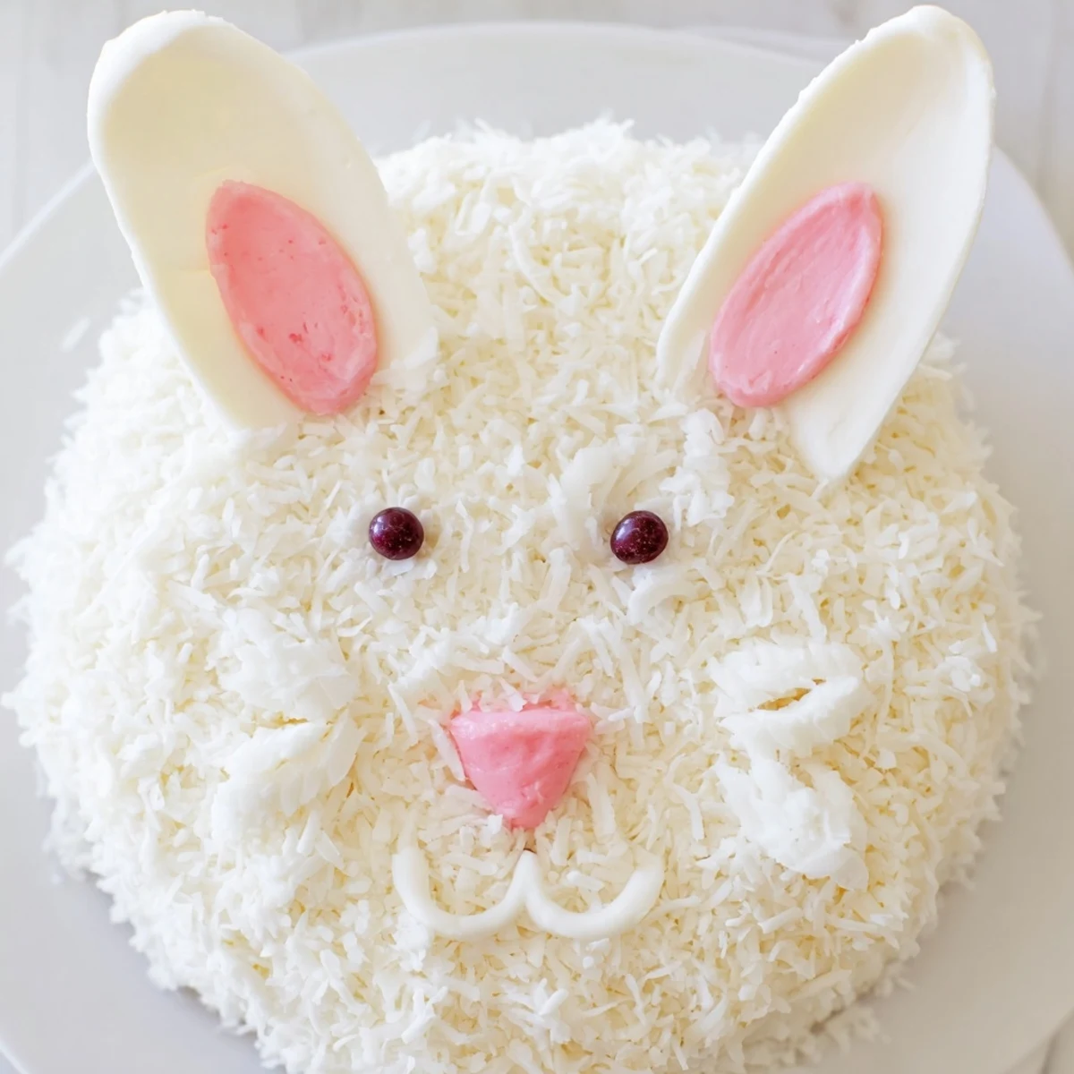 Festive Easter bunny cake decorated with shredded coconut frosting and colorful candy face