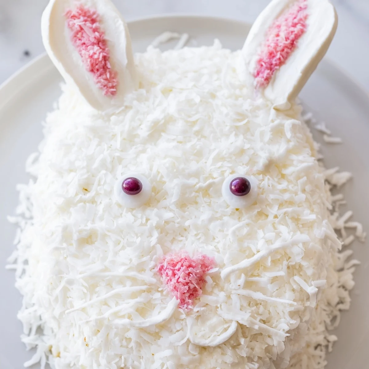 Whimsical bunny shaped vanilla cake covered in buttercream and coconut for spring celebrations