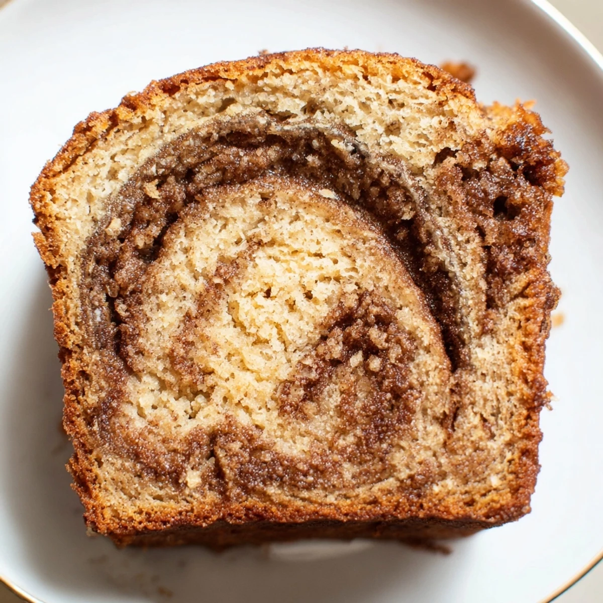 Moist cinnamon sugar swirl banana bread loaf with rippled spiced sugar topping on rustic board