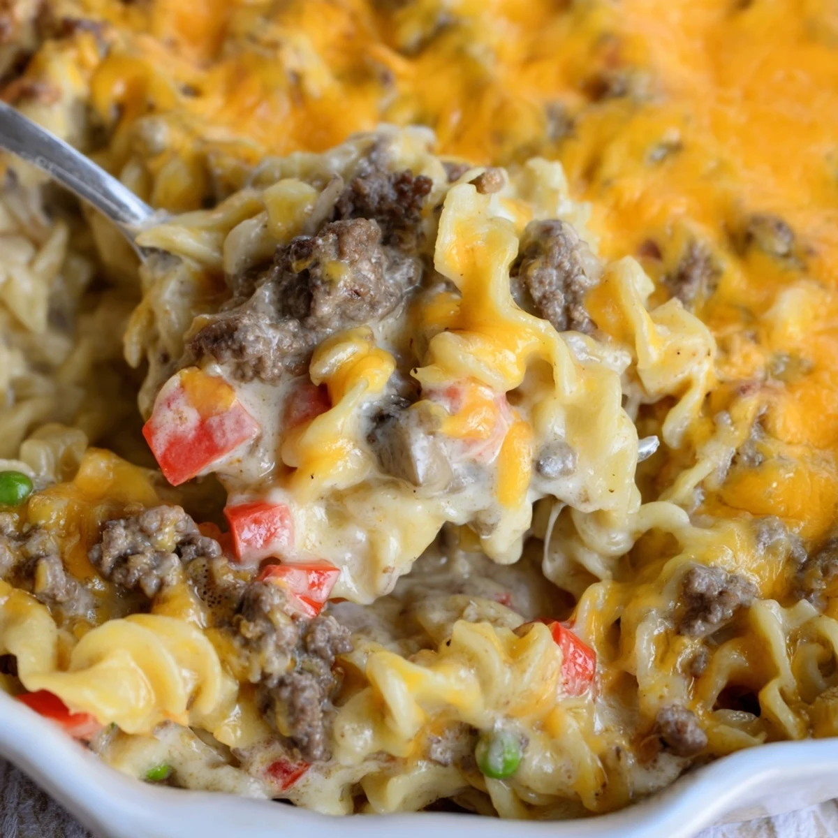 Creamy cheesy beef and noodle casserole served in a white dish with golden crust
