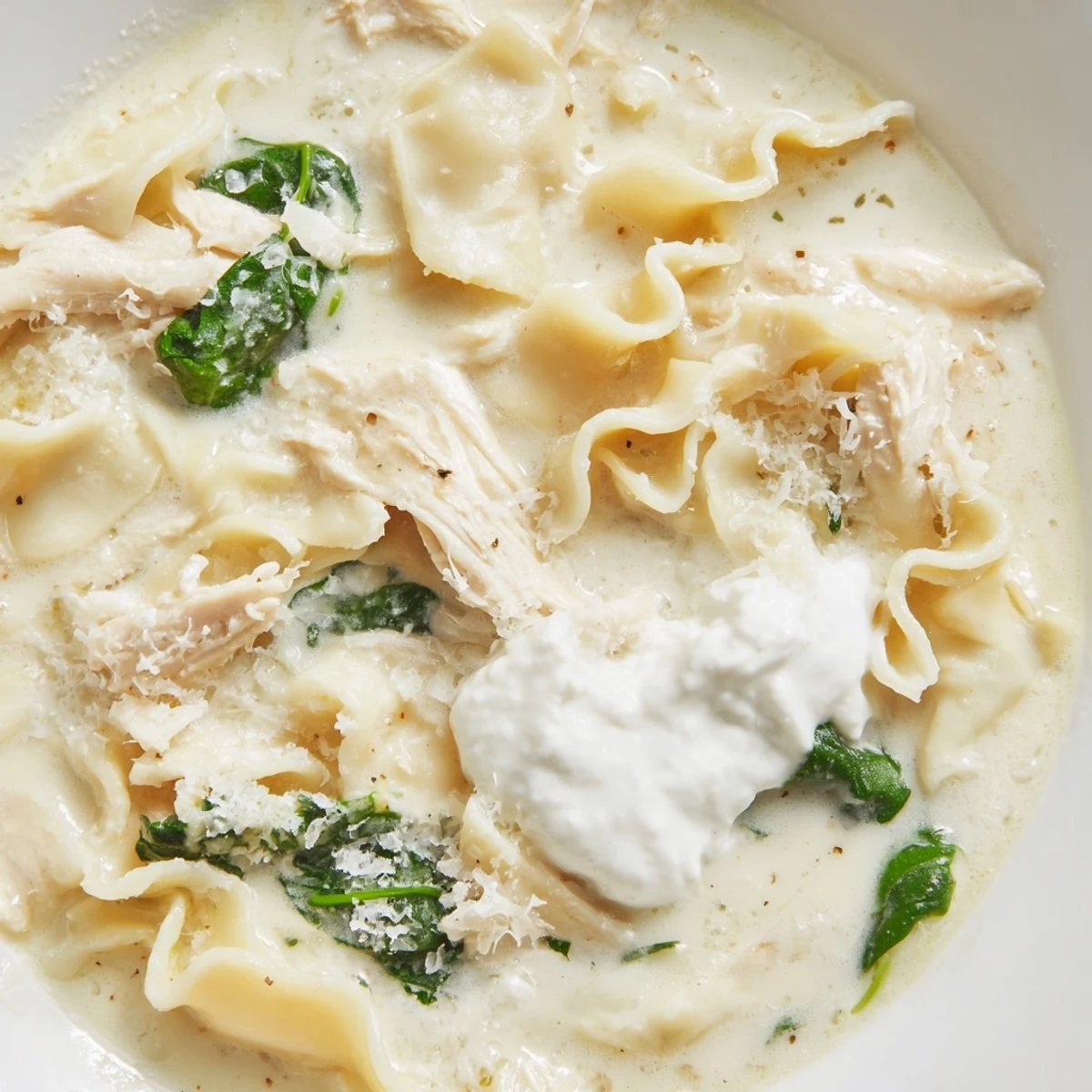 Rich and cheesy white lasagna soup ladled into a cozy mug alongside crusty garlic bread