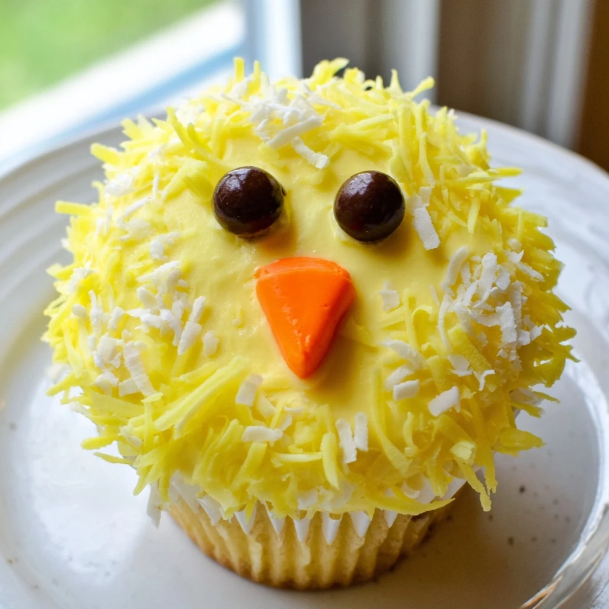 Festive Easter Chick Cupcakes topped with golden buttercream, coconut feathers, and mini chocolate chip eyes ready for celebrating.