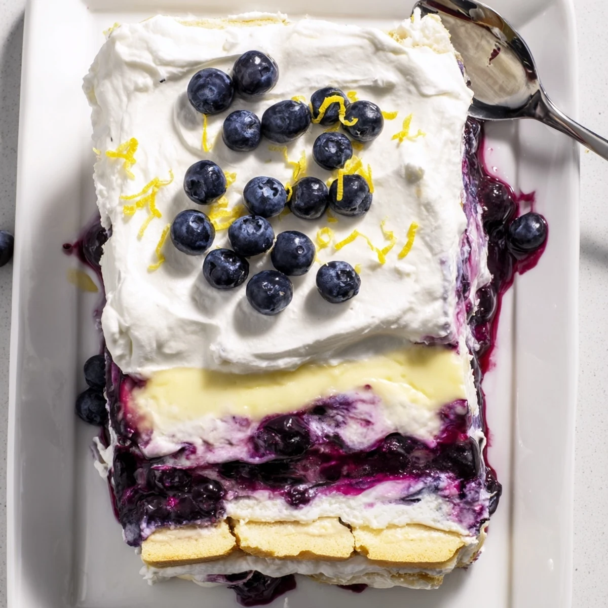 A square of lemon blueberry lasagna showing creamy yellow layers and juicy blueberry filling
