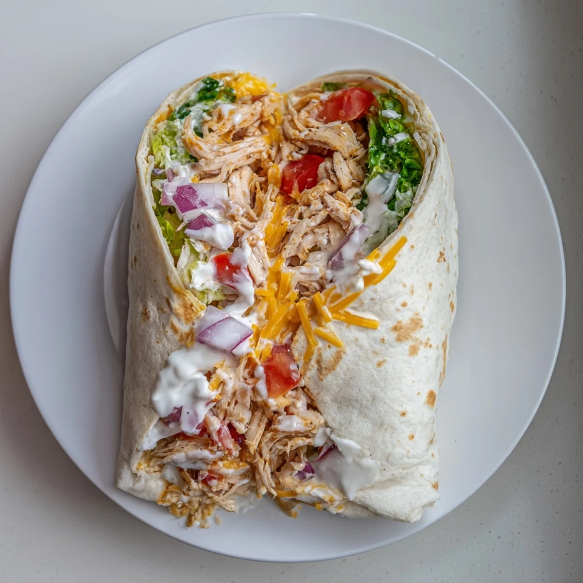 Warm Cheesy Garlic Chicken Wraps sliced in half, gooey cheese, fresh lettuce.