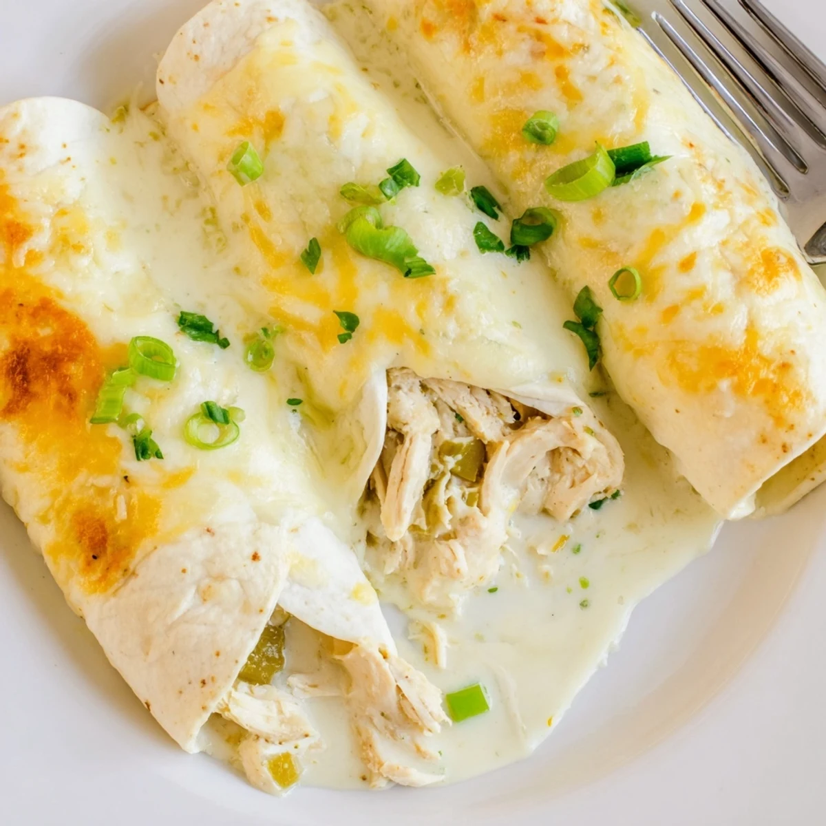 Oven-browned White Rotisserie Chicken Enchiladas plated steaming, cheese stretching