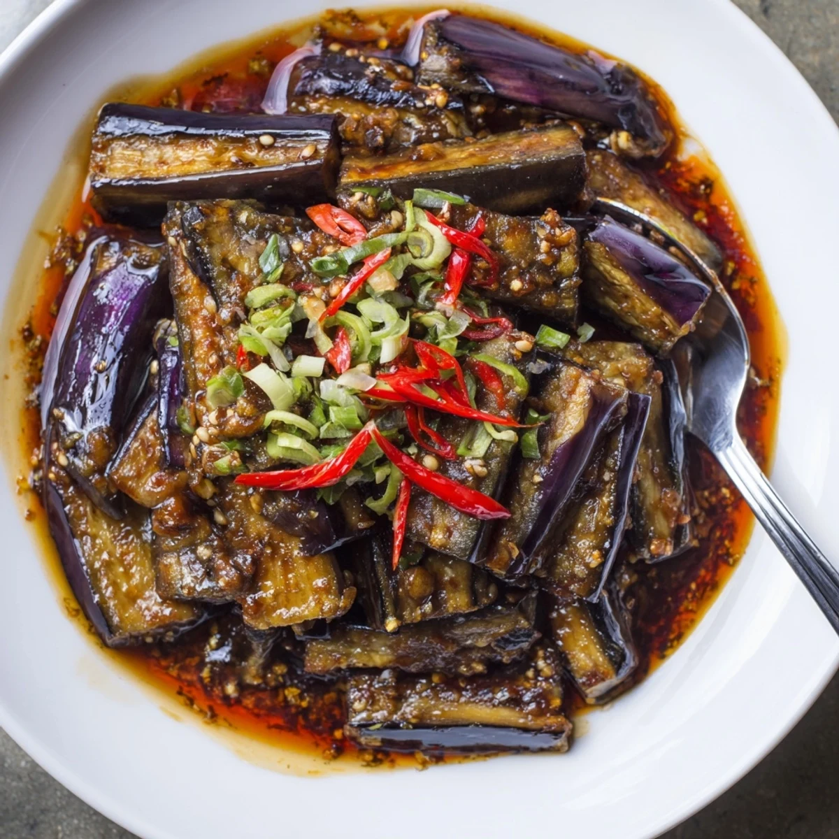 Sichuan Style Braised Aubergines glistening in spicy red sauce, garnished with scallions