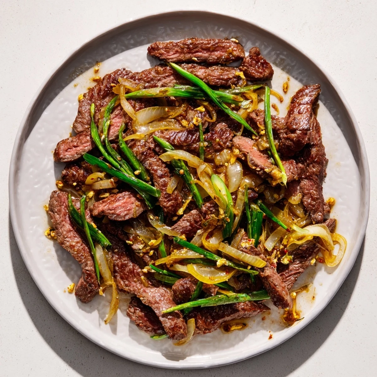 Golden crispy beef strips with caramelized onions in savory sauce glistening under kitchen lights