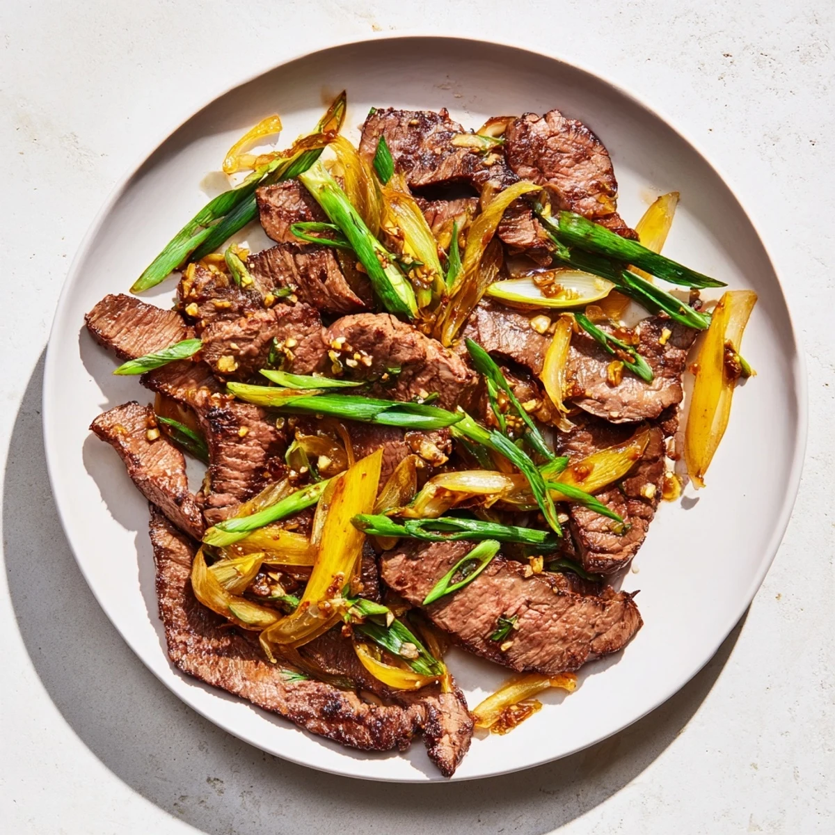 Sizzling skillet of beef and onion stir fry garnished with fresh green spring onions
