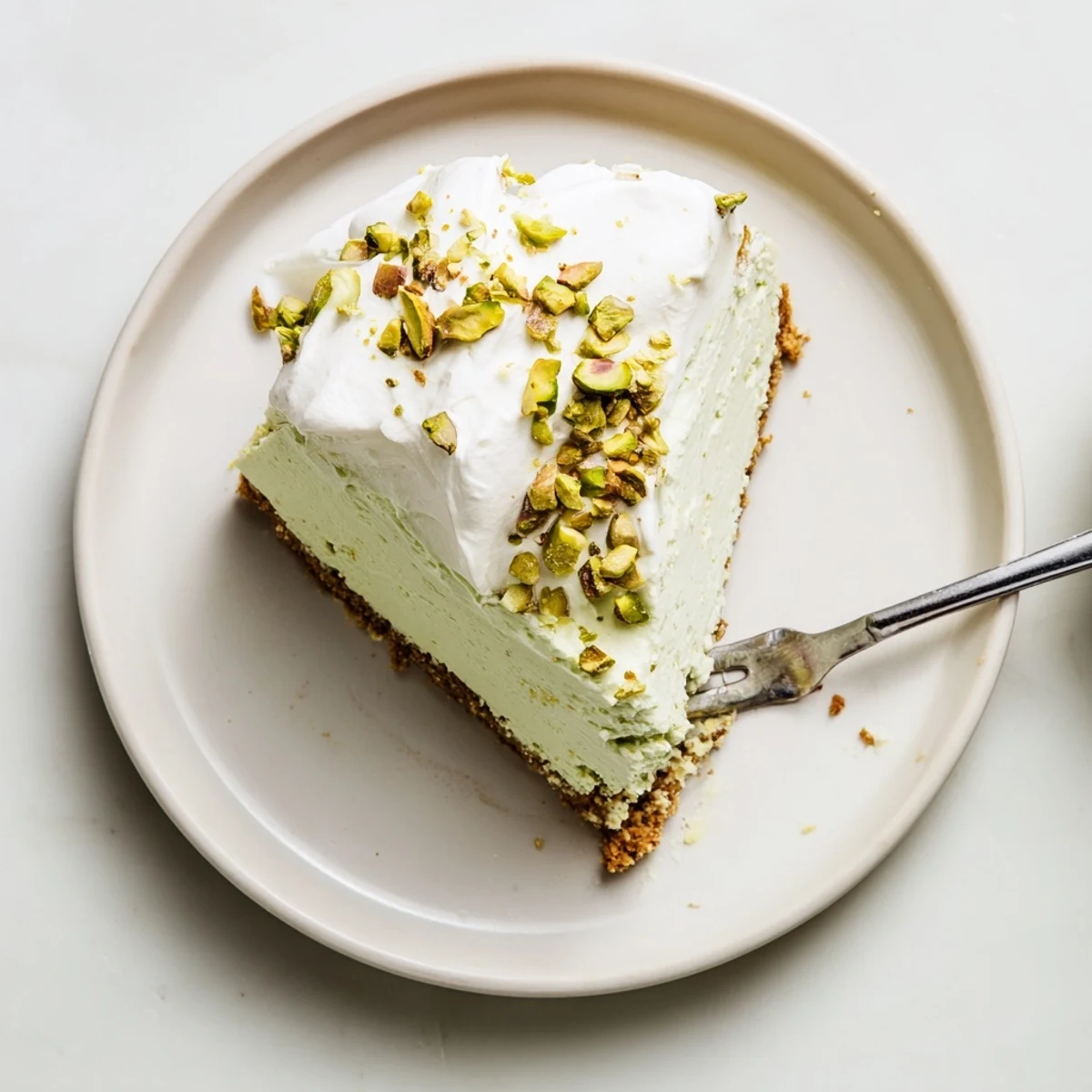 Homemade pistachio cheesecake featuring rich green swirls and crunchy pistachio crust close-up