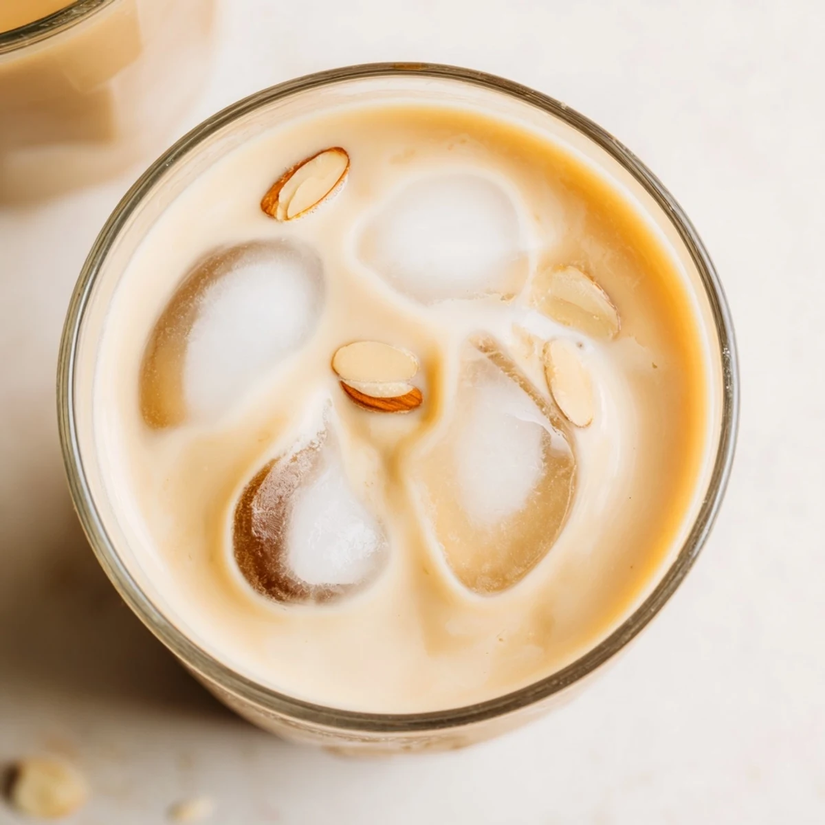 Chilled glass of refreshing summer roasted almond milk drink with cream topped with ice
