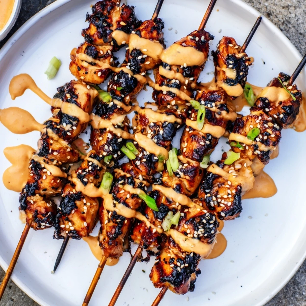 Grilled Bang Bang Chicken Skewers glistening with creamy spicy sauce and sesame seeds